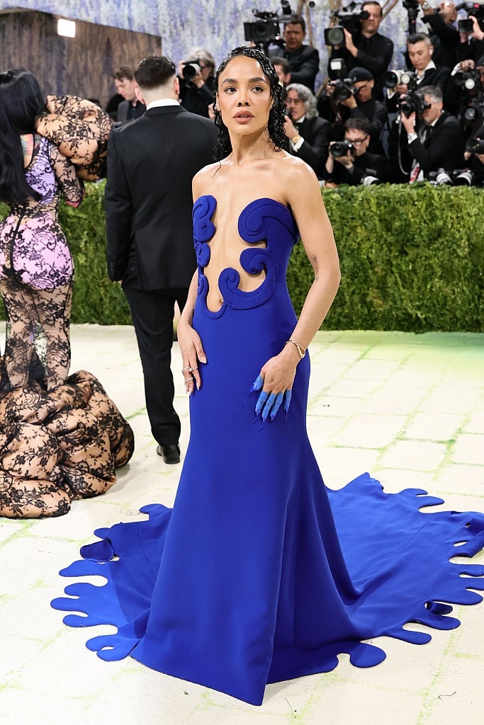Person successful  elegant, creator  gown connected  the reddish  carpet, attended by photographers
