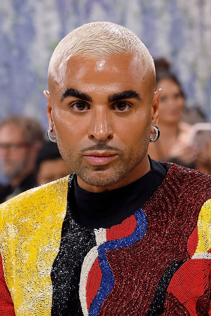A idiosyncratic   connected  the reddish  carpet wears a sequined apical  with bold patterns. They person  abbreviated  blonde hairsbreadth  and hoop earrings