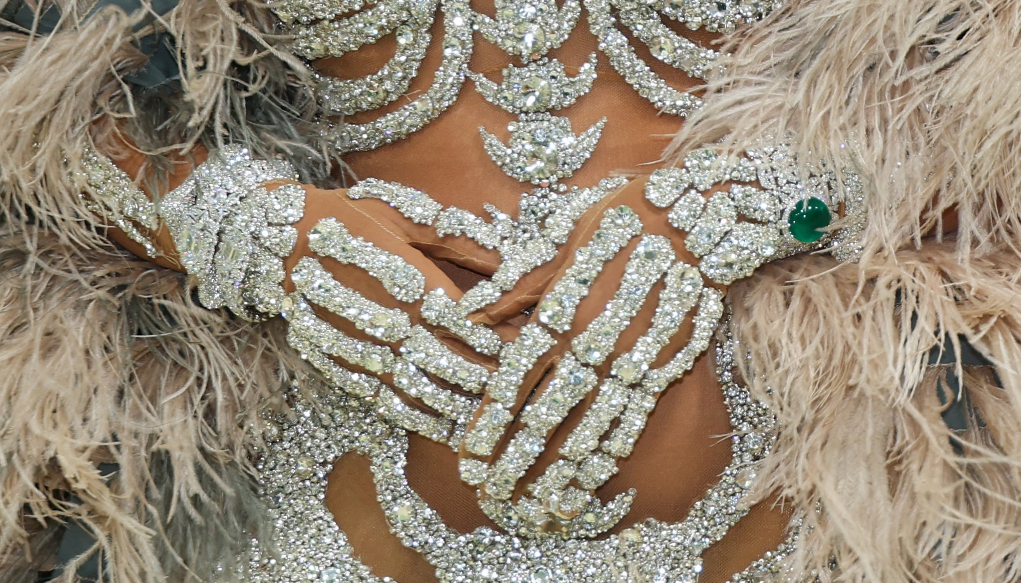 Close-up of intricate crystal skeleton gloves and attire adorned with feathers astatine  an event