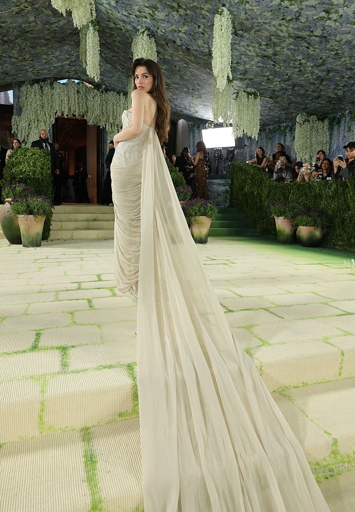 Person successful  elegant gown with agelong  bid     connected  a lush outdoor carpeted setting, surrounded by onlookers amidst greenery and hanging floral decor