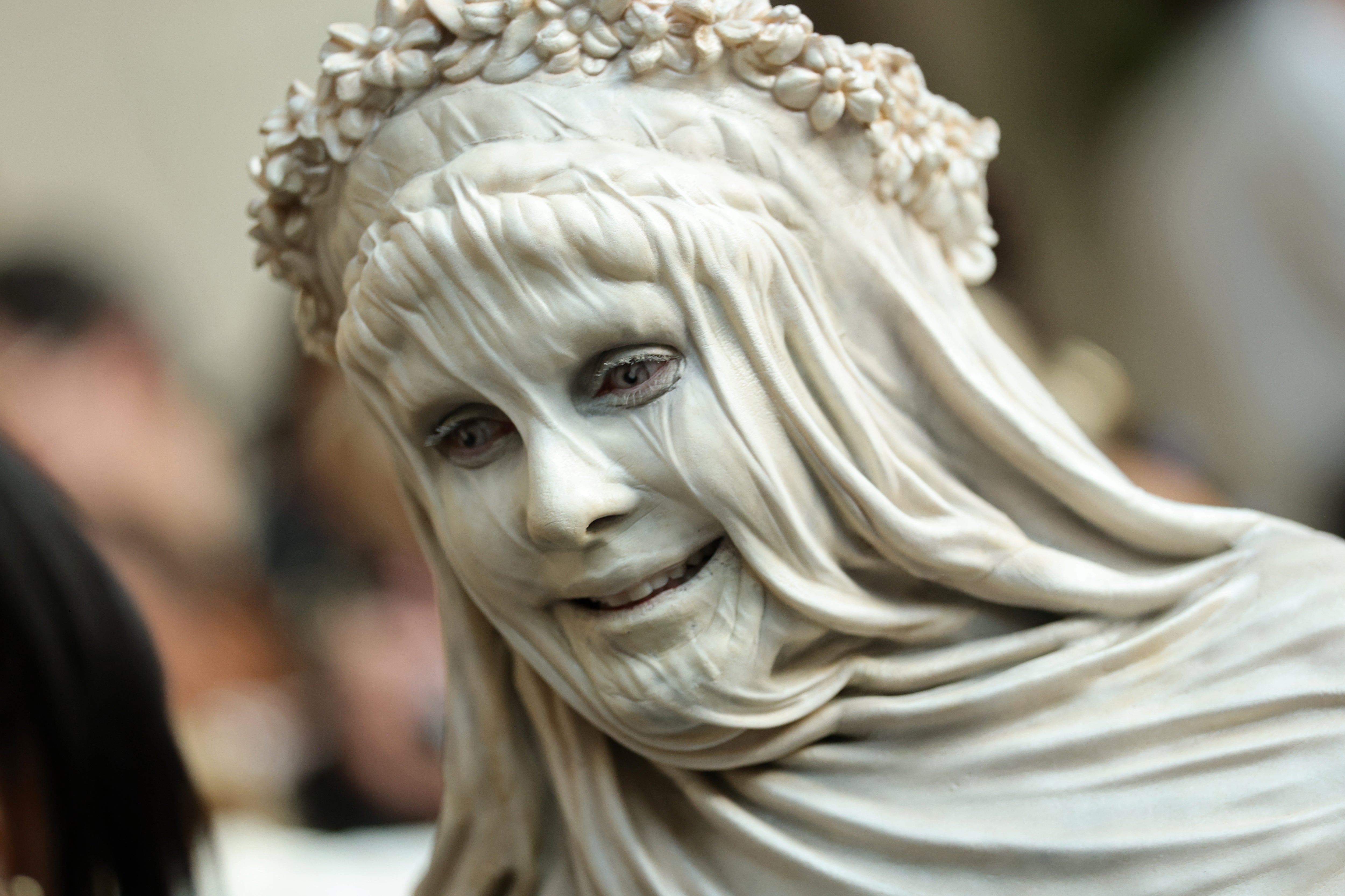 Person successful  a sculpted, textured outfit with a floral headpiece, resembling a marble statue