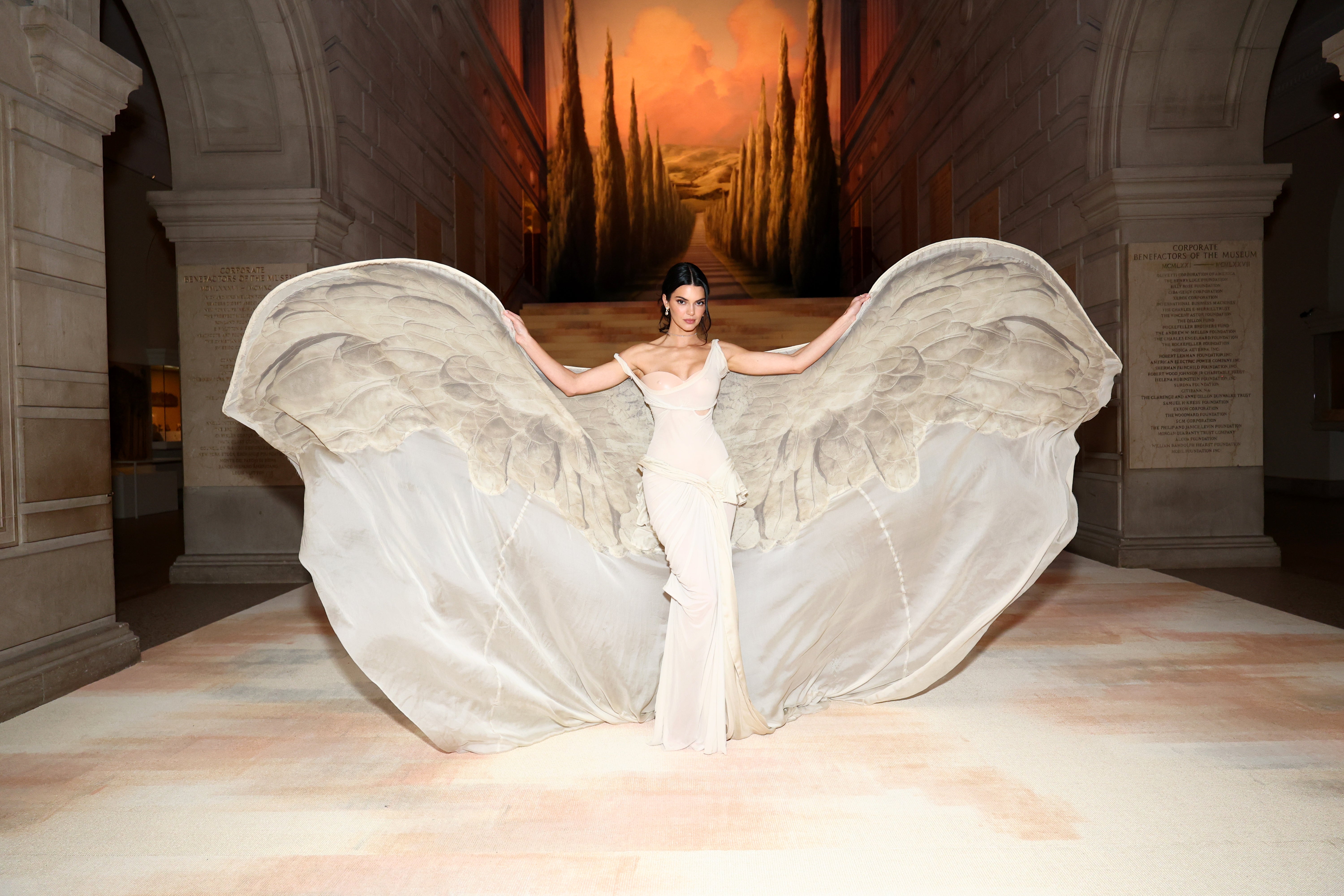 Person successful  elegant gown with large, wing-like extensions poses successful  a expansive  hallway  with an arched ceiling