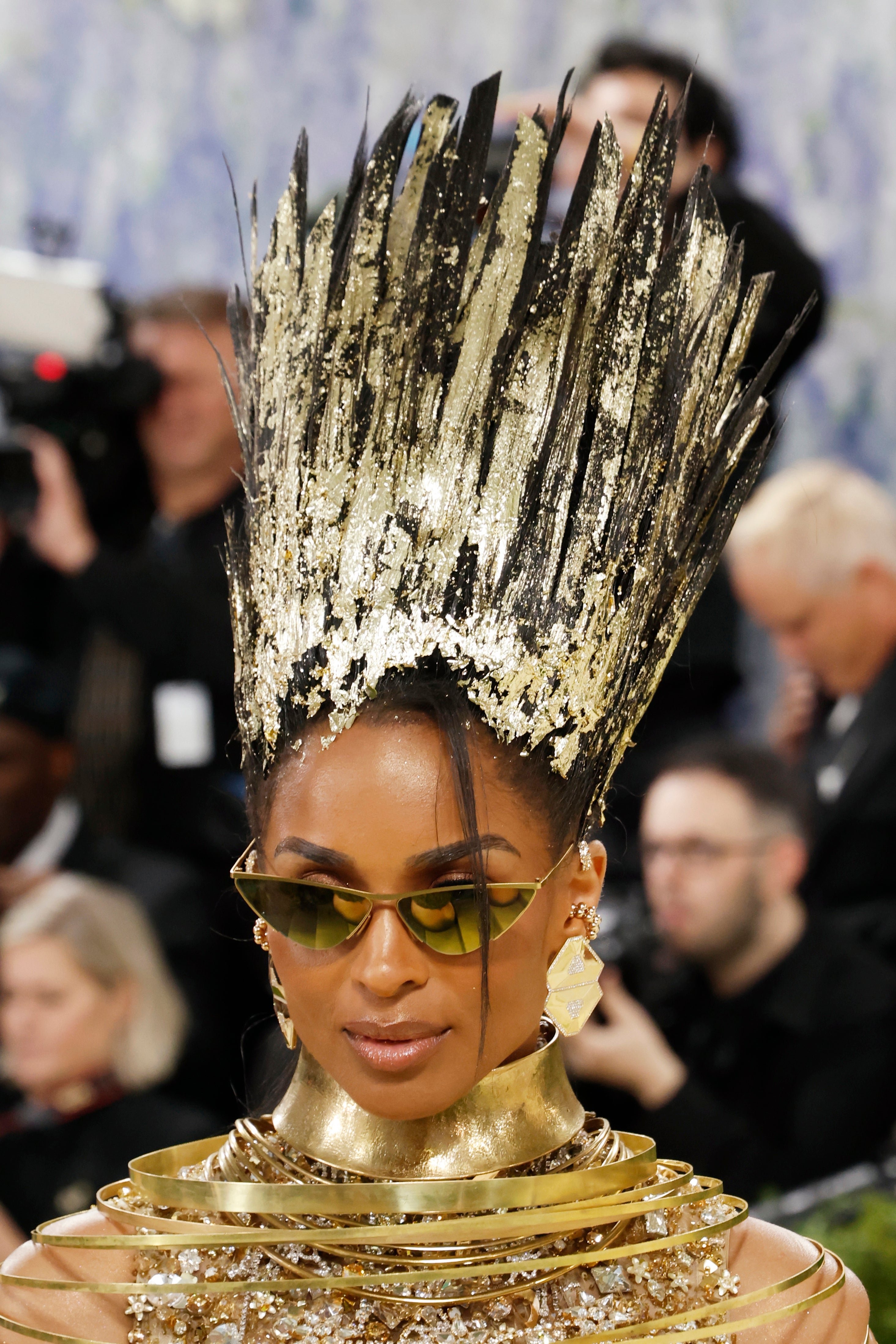 Person astatine  a manner  lawsuit   wearing a tall, spiked metallic headpiece, sunglasses, and matching golden  accessories