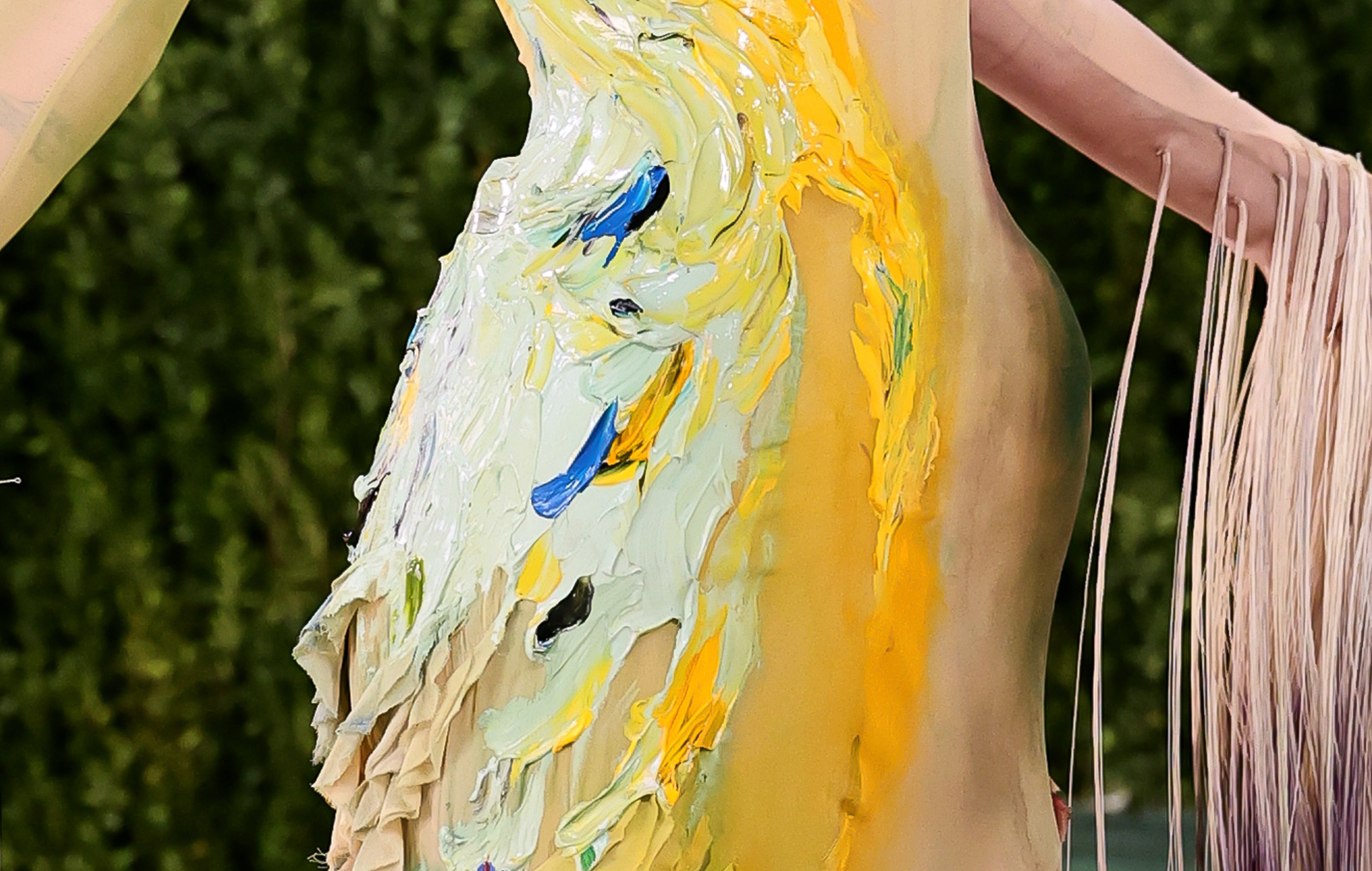 Close-up of a textured formal  with abstract, paint-like designs successful  yellowish  and blue, featuring long, dangling sleeves