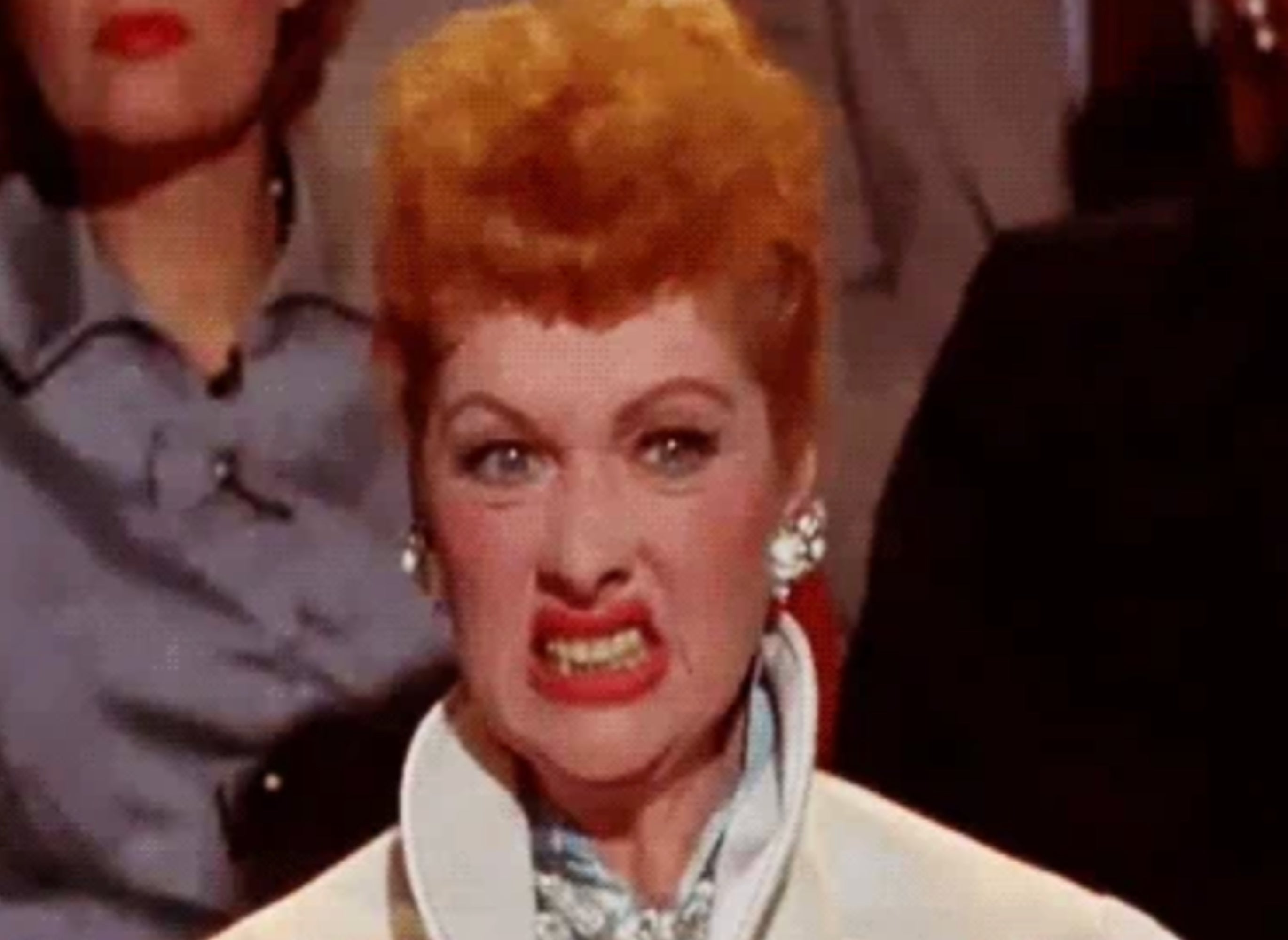 Person with a dramatic, exaggerated expression, wearing elegant attire, seen in a seated setting