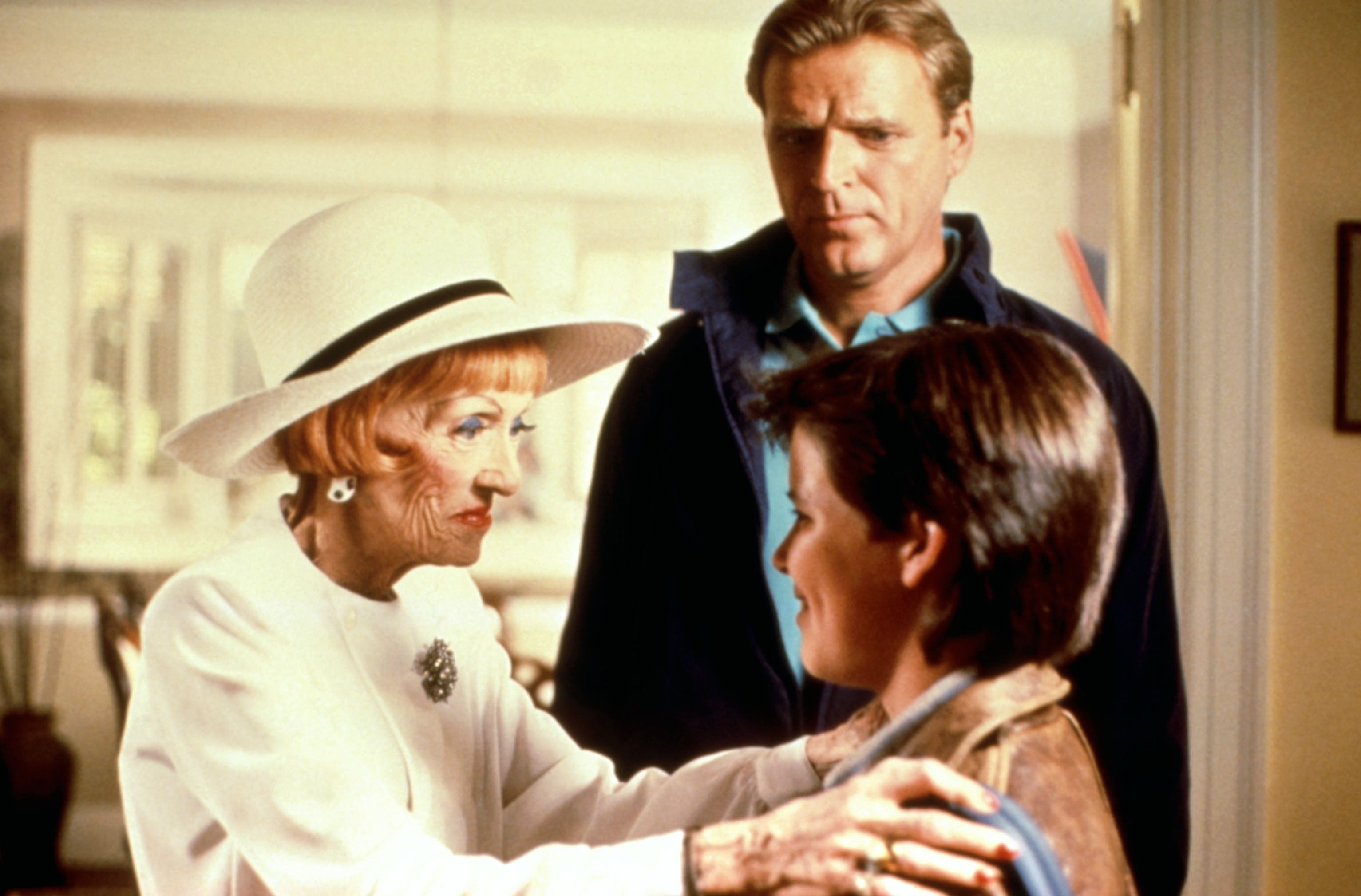 An older pistillate   successful  a achromatic  outfit and chapeau  talks to a young man, portion    different  antheral   stands down  them, looking connected  with concern