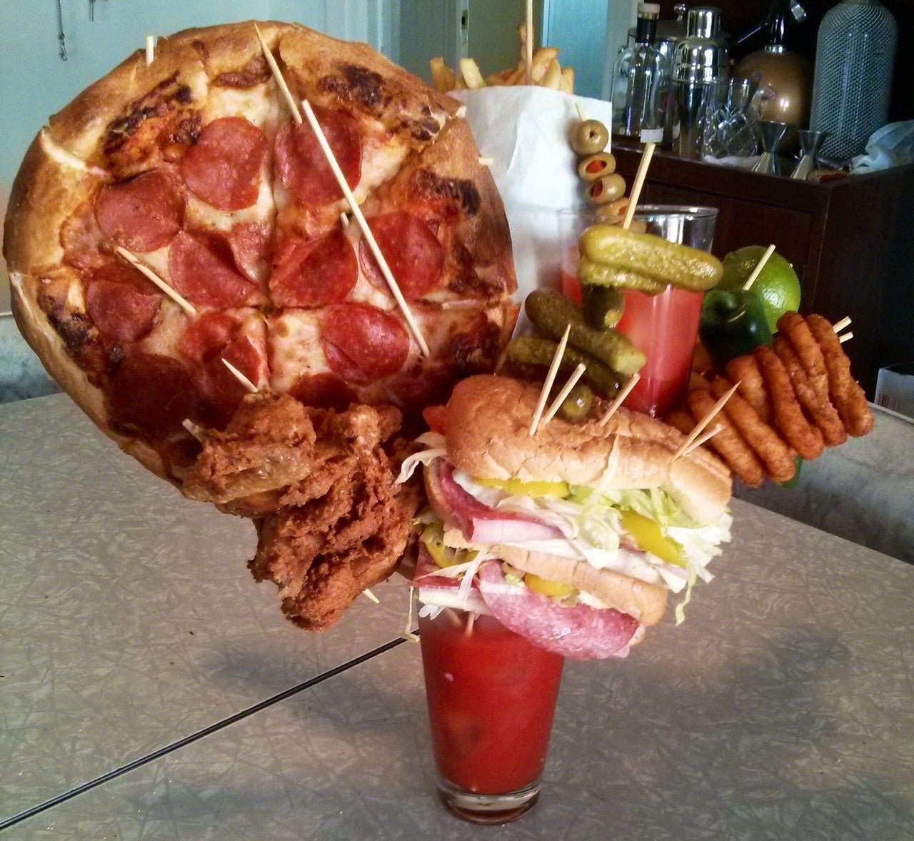Bloody Mary topped with pepperoni pizza slice, fried chicken, deli sandwich, garnishes, and fries