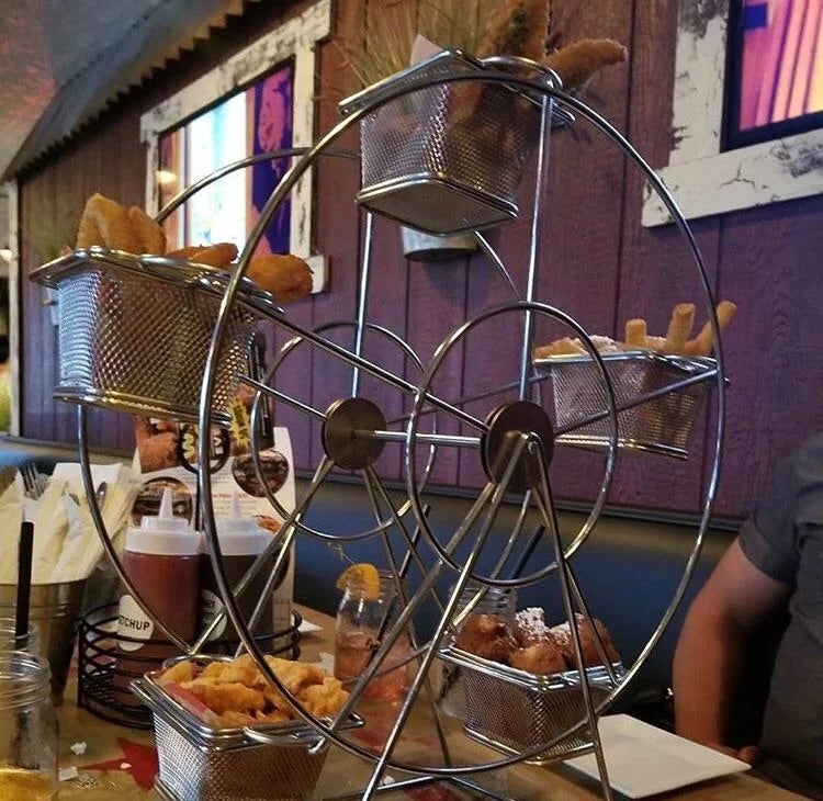 Ferris wheel-shaped food holder on a table, displaying various fried snacks in baskets