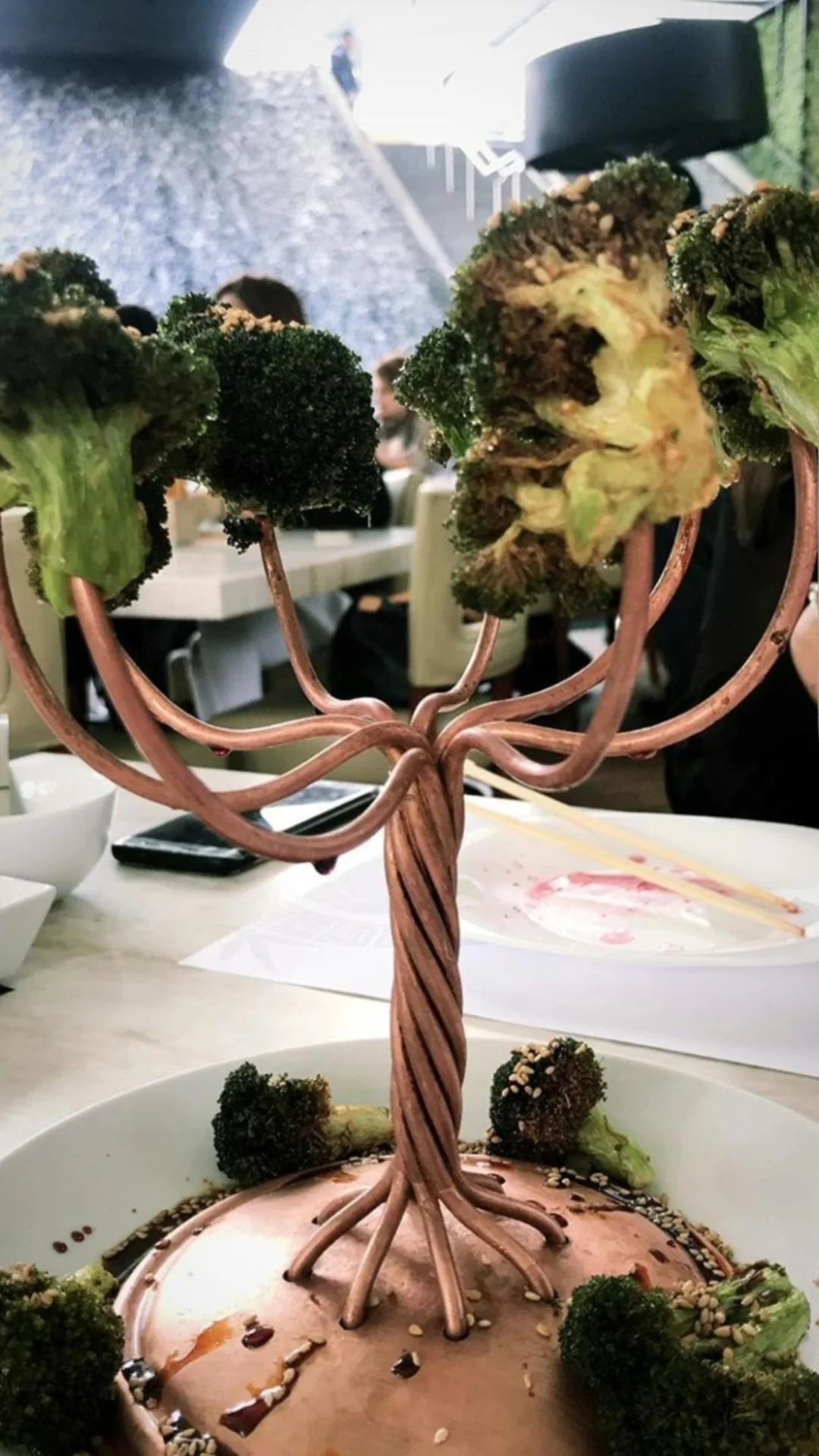 Broccoli florets arranged like a tree on a decorative stand at a restaurant