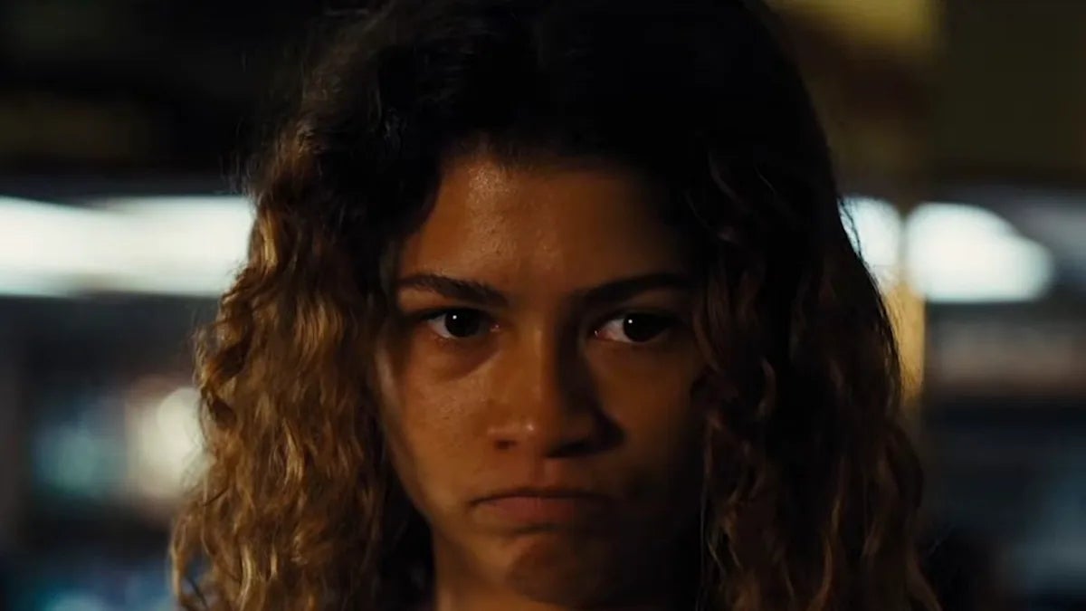 Person with curly hair appears concerned and introspective, set in an indoor environment