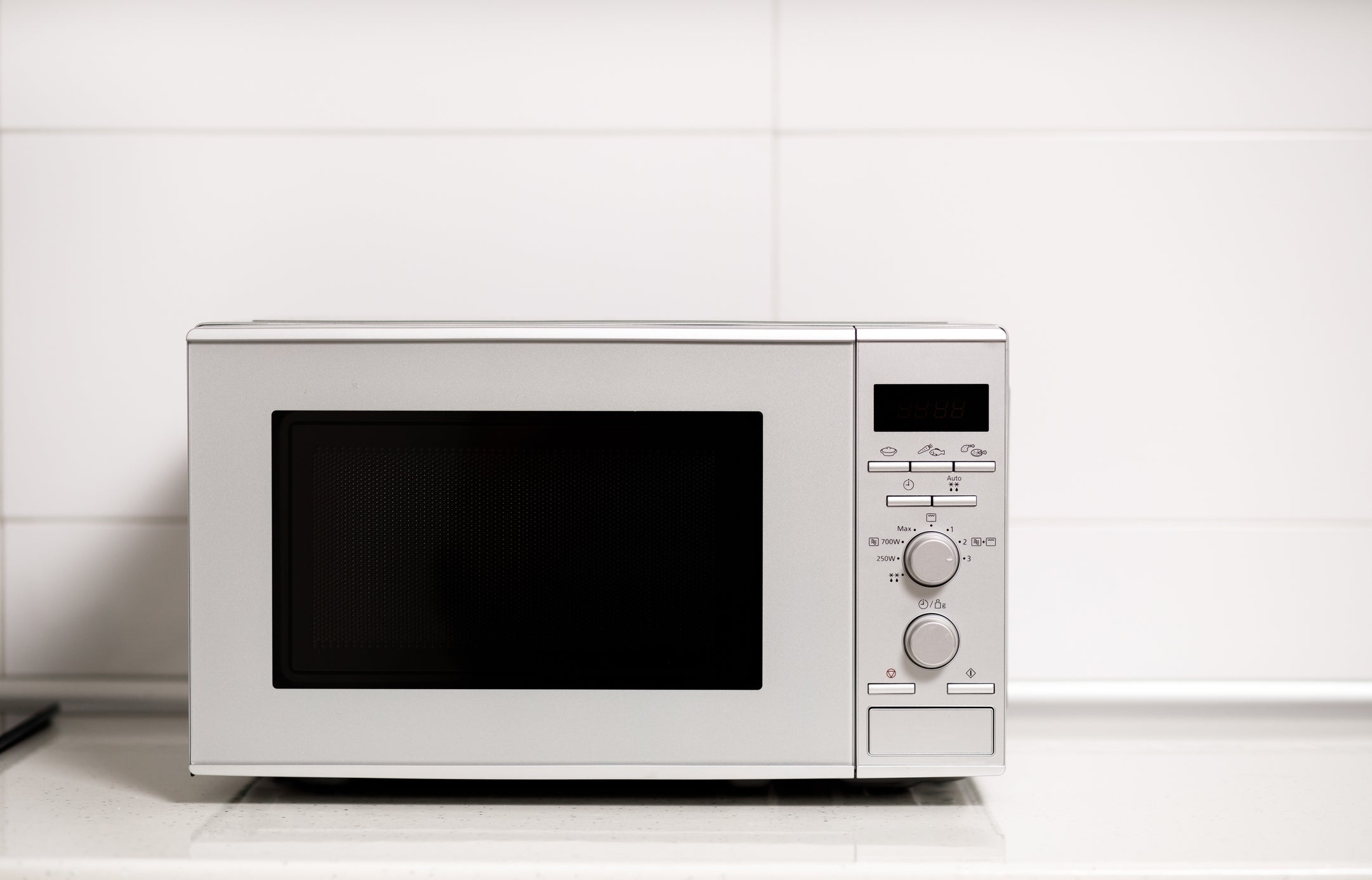 Microwave on a kitchen counter with control knobs and a digital display