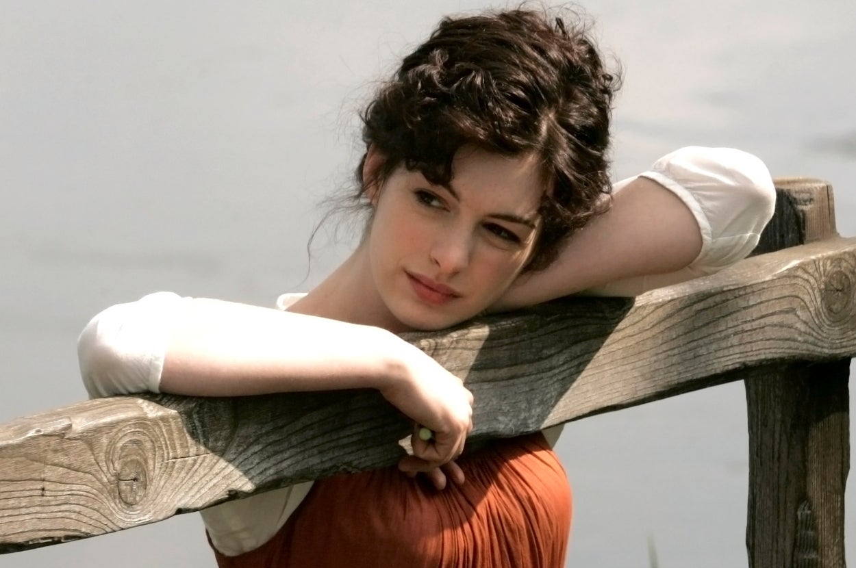 Anne Hathaway in "Becoming Jane" leaning on a wooden fence, looking thoughtful