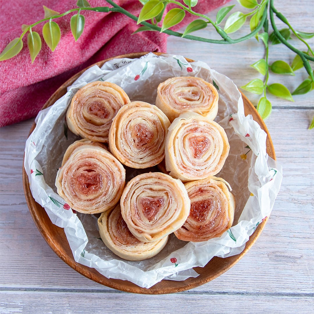 春巻きの皮を使ったお菓子が並んでいる。バックには赤い布と植物が配置されている。