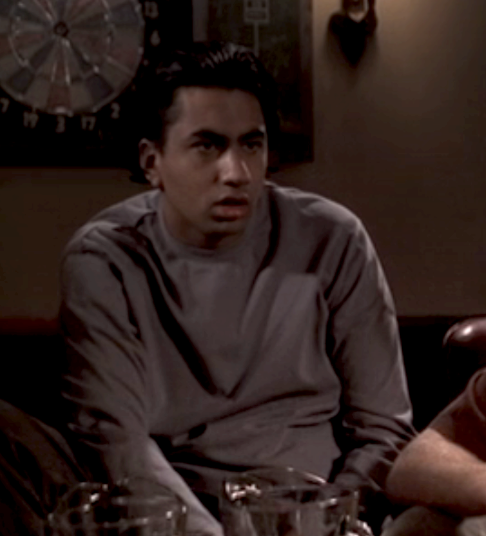 Person sitting successful  a dimly lit room, looking dumbfounded; dartboard connected  the partition  successful  the background