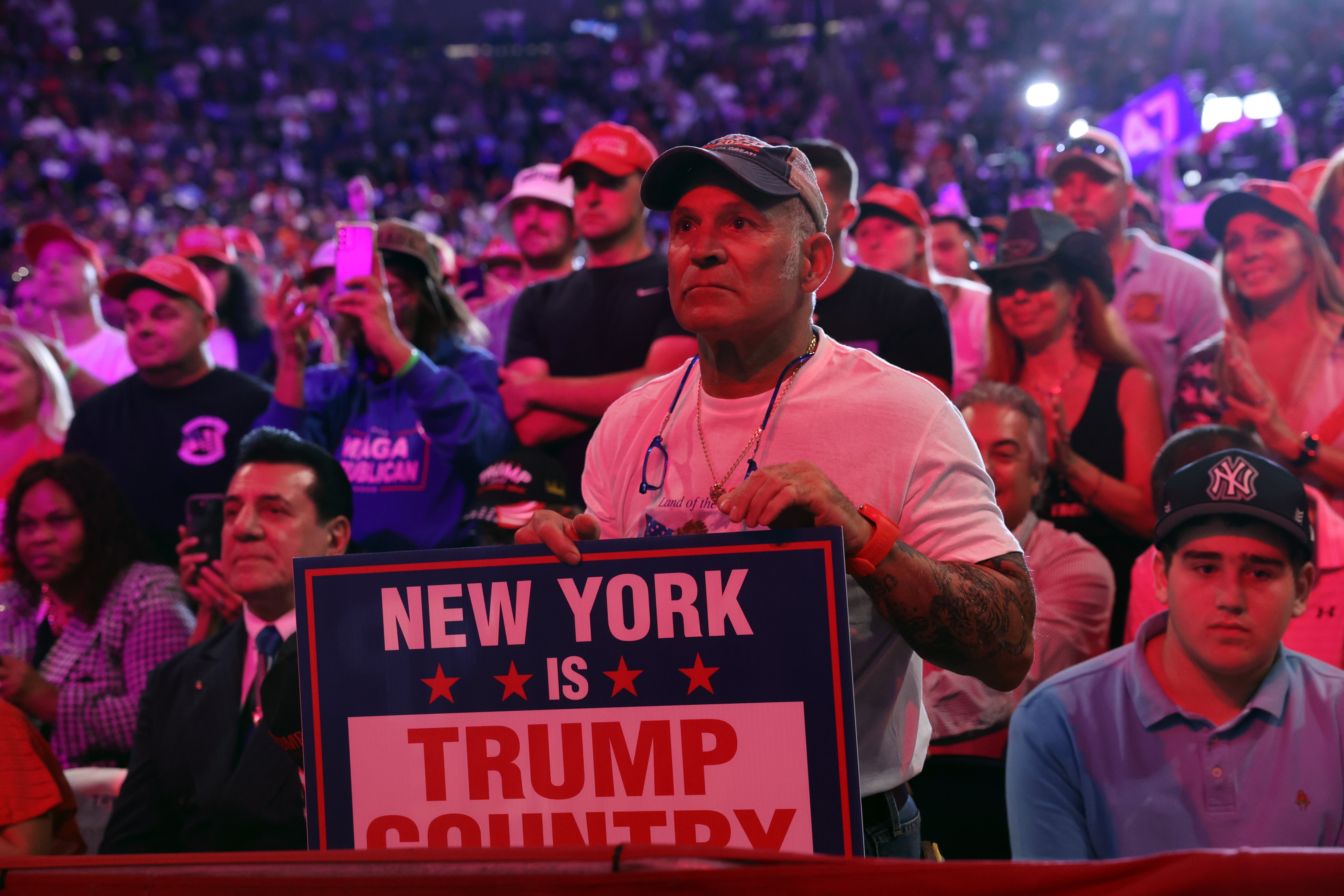 Crowd astatine  a rally, antheral   successful  foreground holds "New York is Trump Country" sign, attendees are focused connected  an unseen speaker