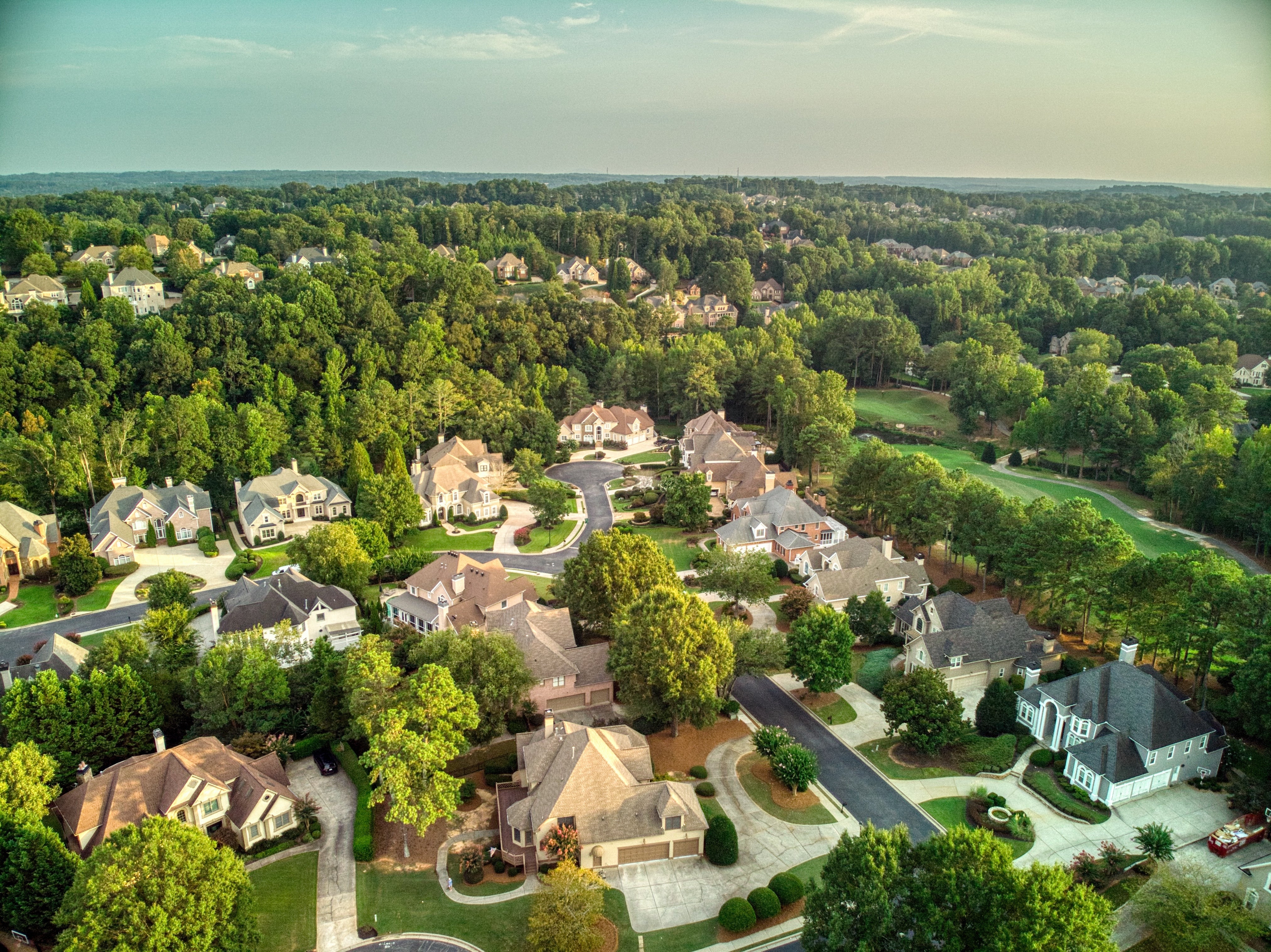 Aerial presumption    of a suburban vicinity  with houses surrounded by trees and curved streets