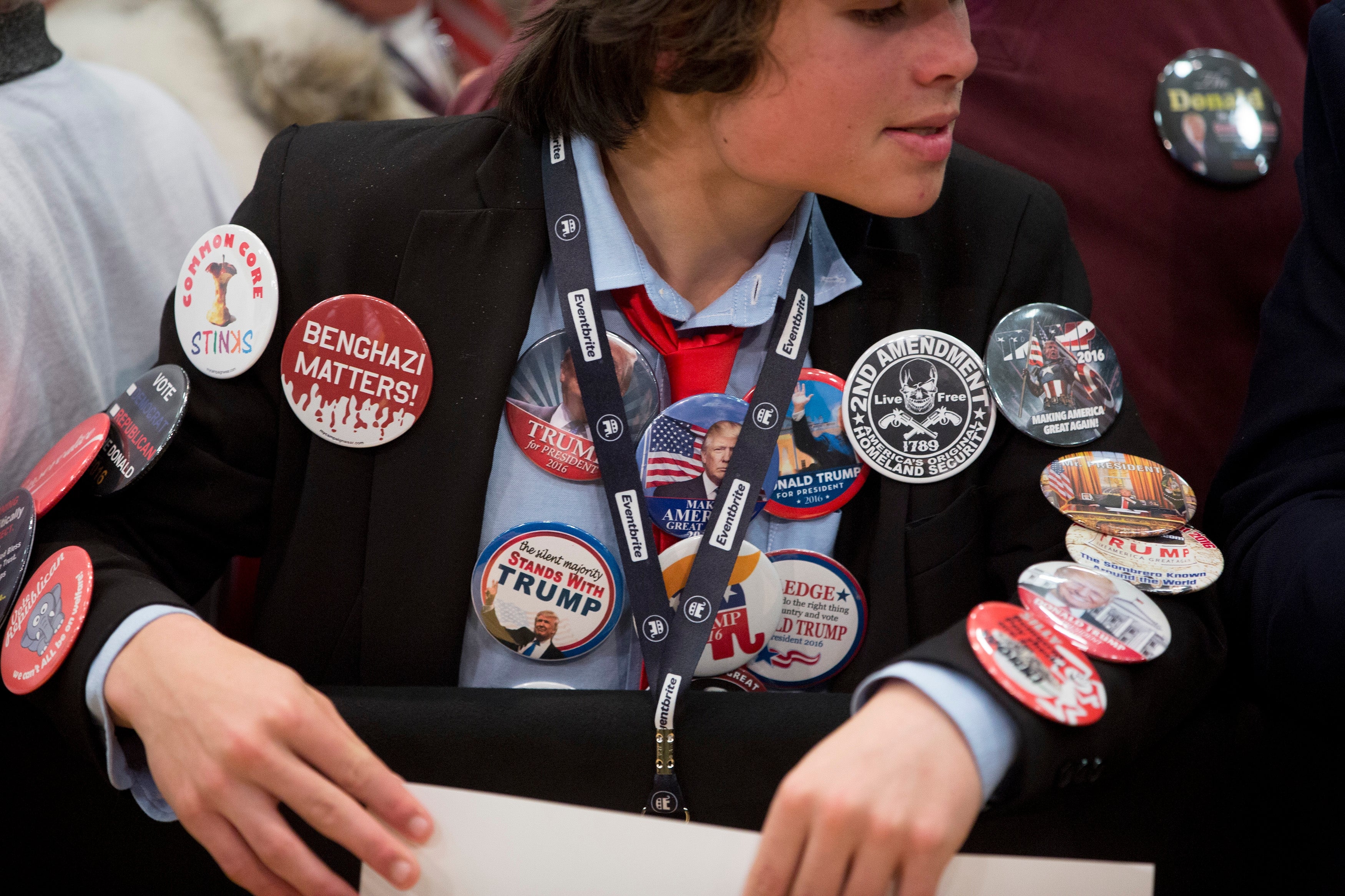 Person successful  a suit   with galore   governmental  run  buttons connected  their jacket, including slogans supporting Trump and mentioning Benghazi