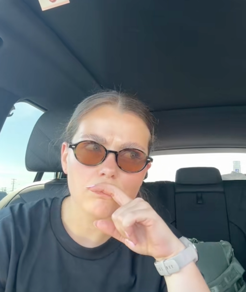 Person successful  sunglasses seated successful  a car, wearing a graphic T-shirt, looking thoughtful