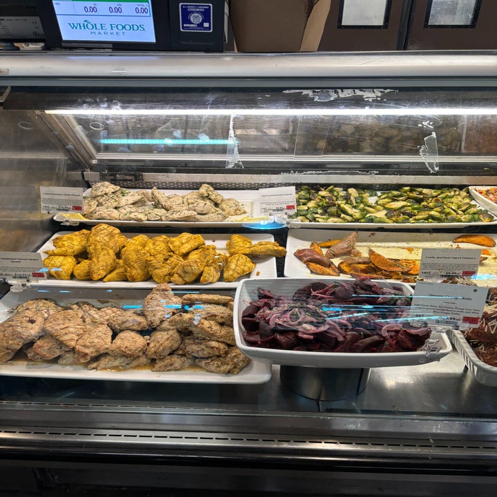 Deli counter with various prepared foods on display, including chicken and vegetables
