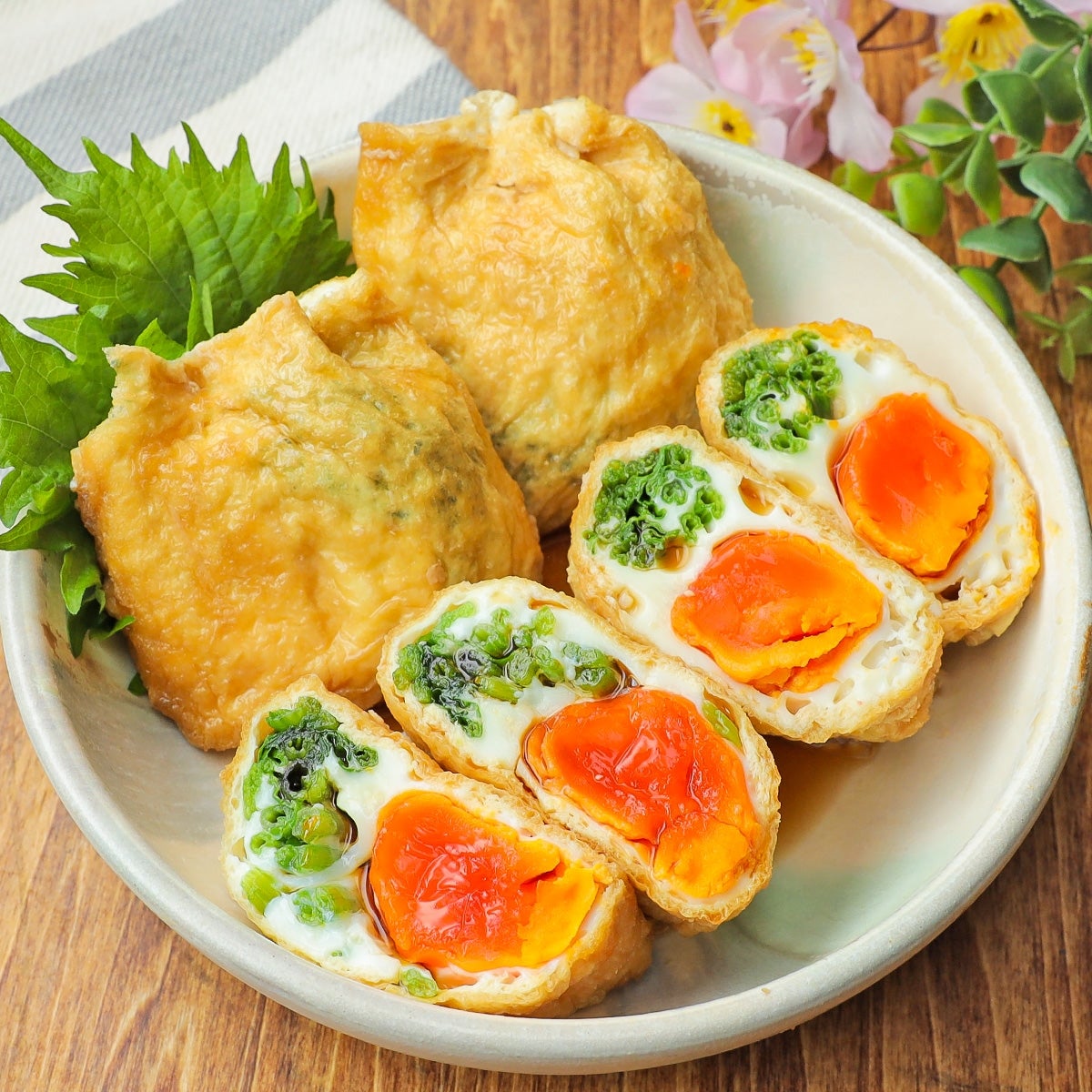 料理が盛られた皿。揚げ豆腐の中に卵と野菜が詰まっており、隣に緑の葉が添えられている。