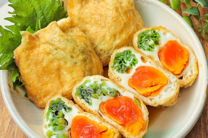 料理が盛られた皿。揚げ豆腐の中に卵と野菜が詰まっており、隣に緑の葉が添えられている。
