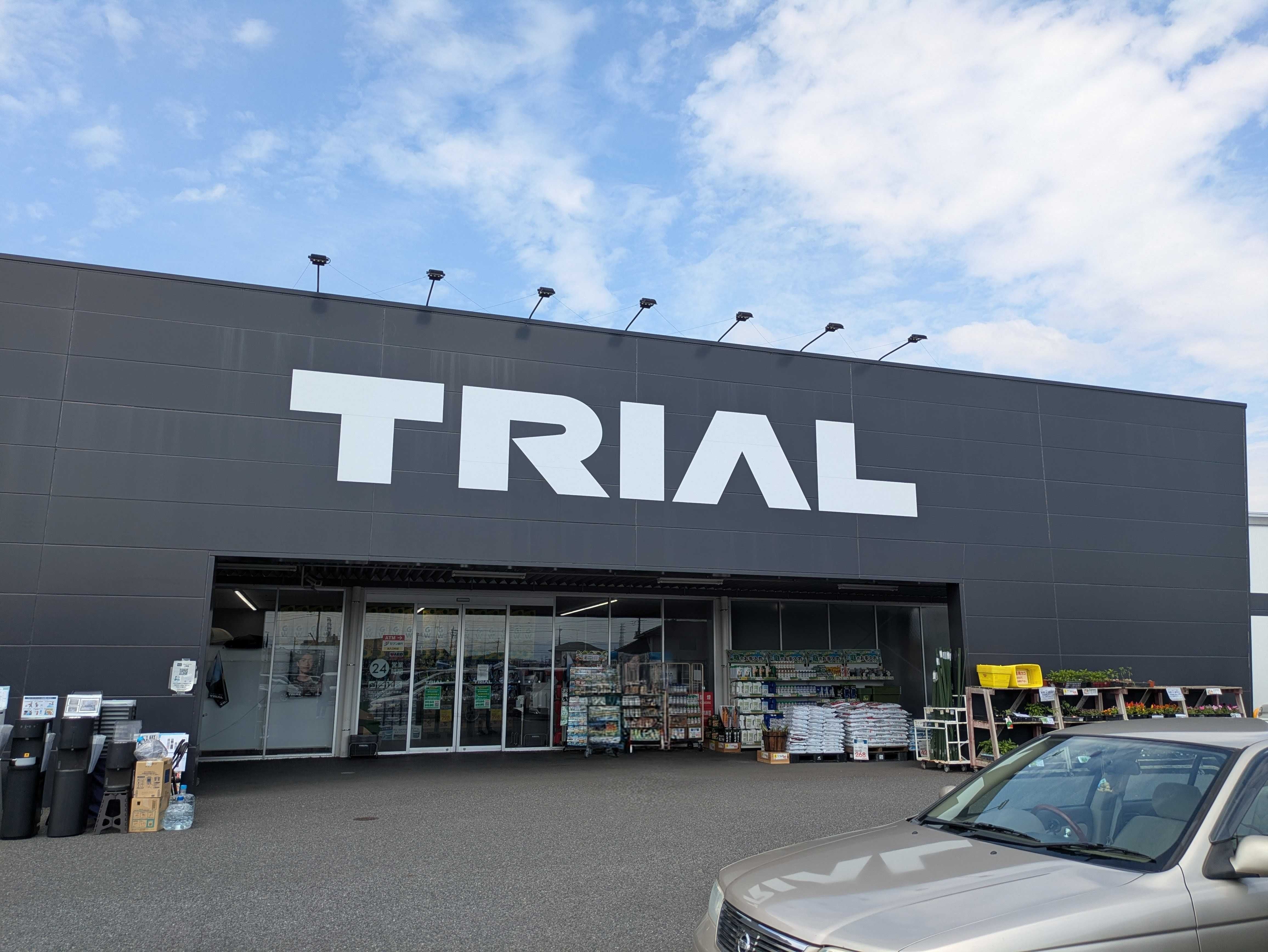 ディスカウントストア「TRIAL」の外観。駐車場に車が止まっている。青空の下に位置している。