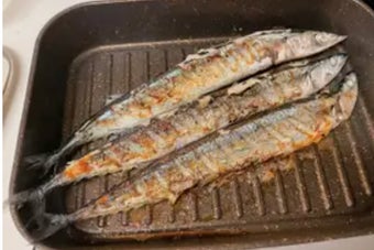 左のフライパンには生の魚が3匹、右のフライパンには焼き上がった魚が3匹。