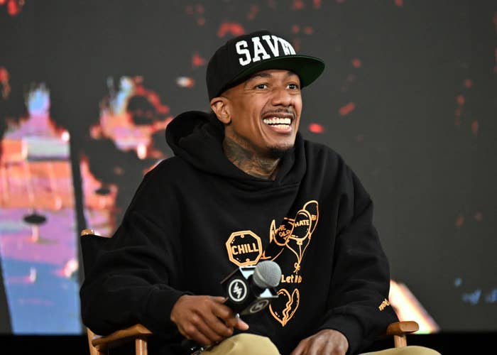 Person successful  a hoodie and headdress  speaking connected  signifier    during an event, sitting successful  a director's seat  and smiling