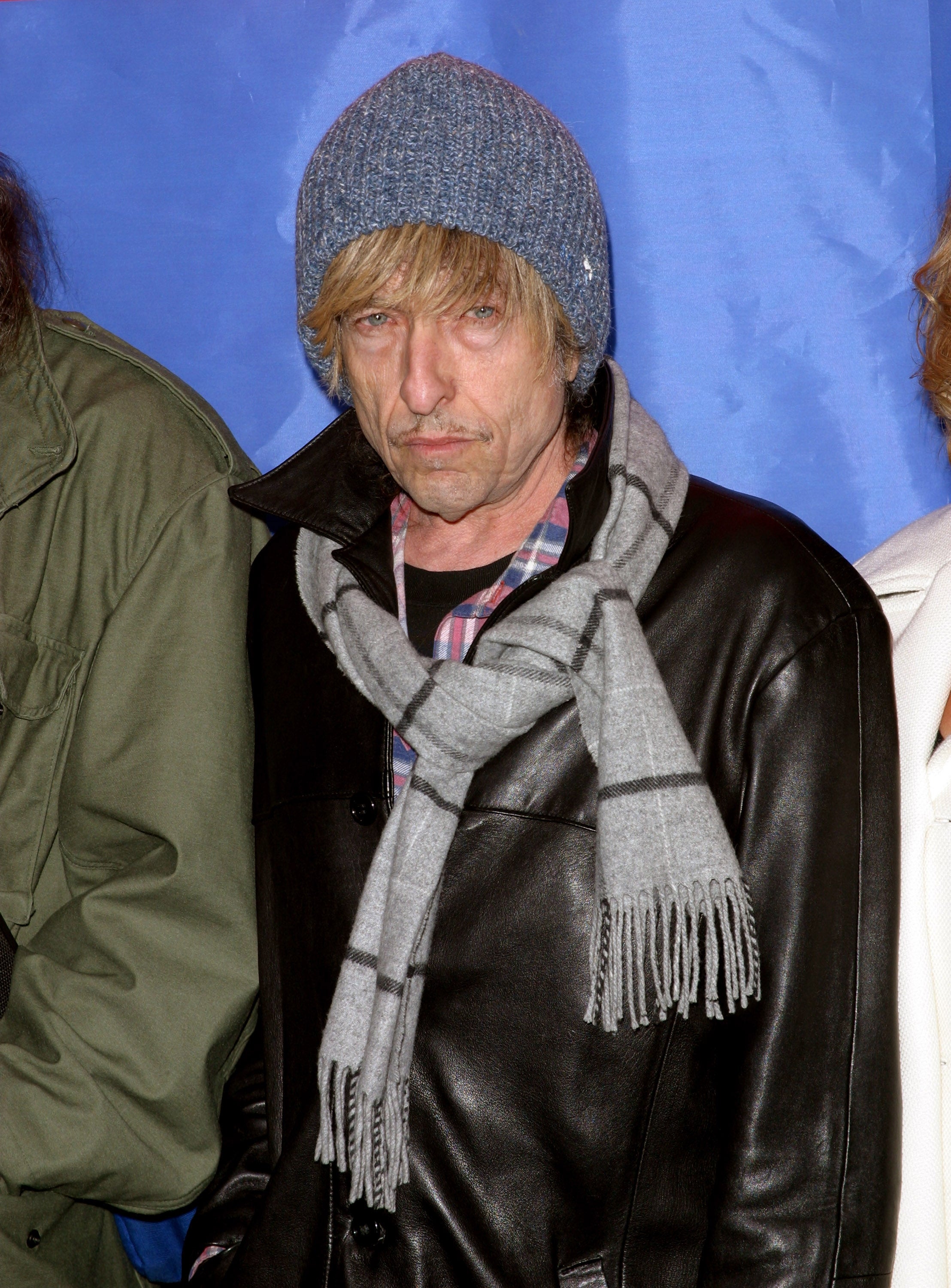 Bob Dylan successful  a plaid shirt, leather jacket, scarf, and knit beanie, posing astatine  an event