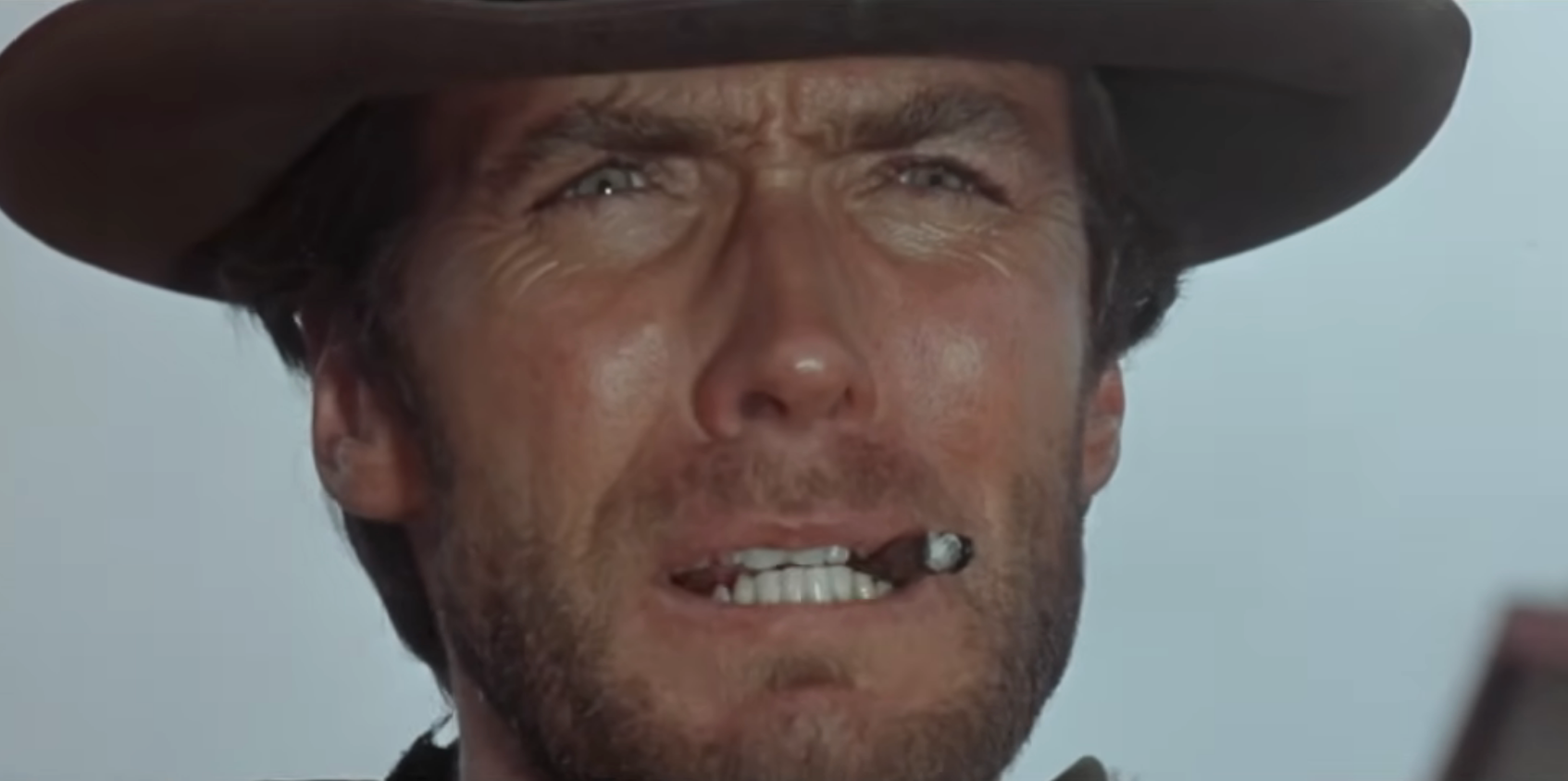 A idiosyncratic   wearing a cowboy chapeau  with a cigar successful  their mouth, looking intensely into the distance