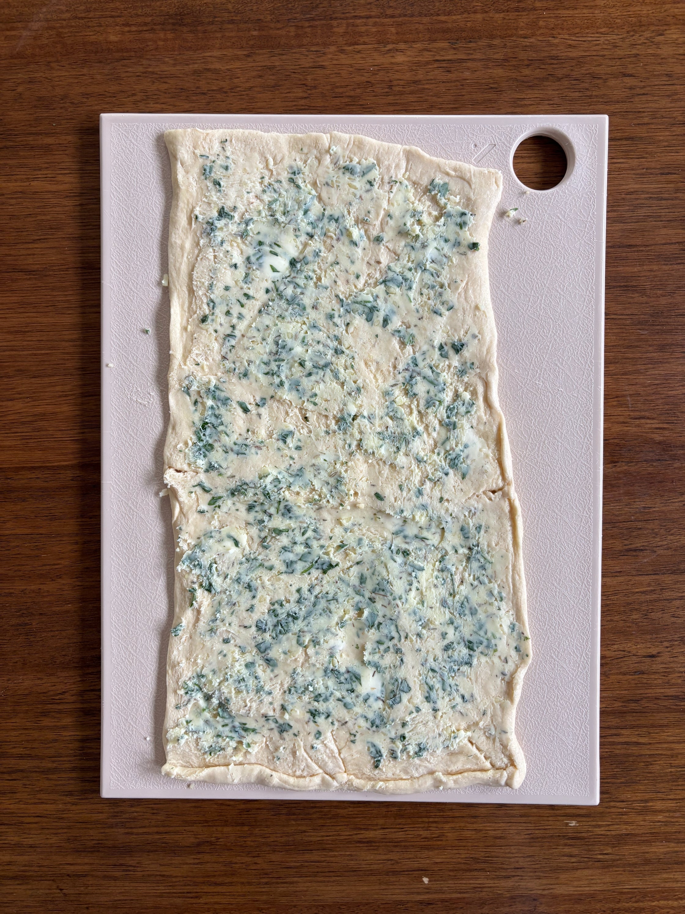 Pastry dough with herb butter on cutting board