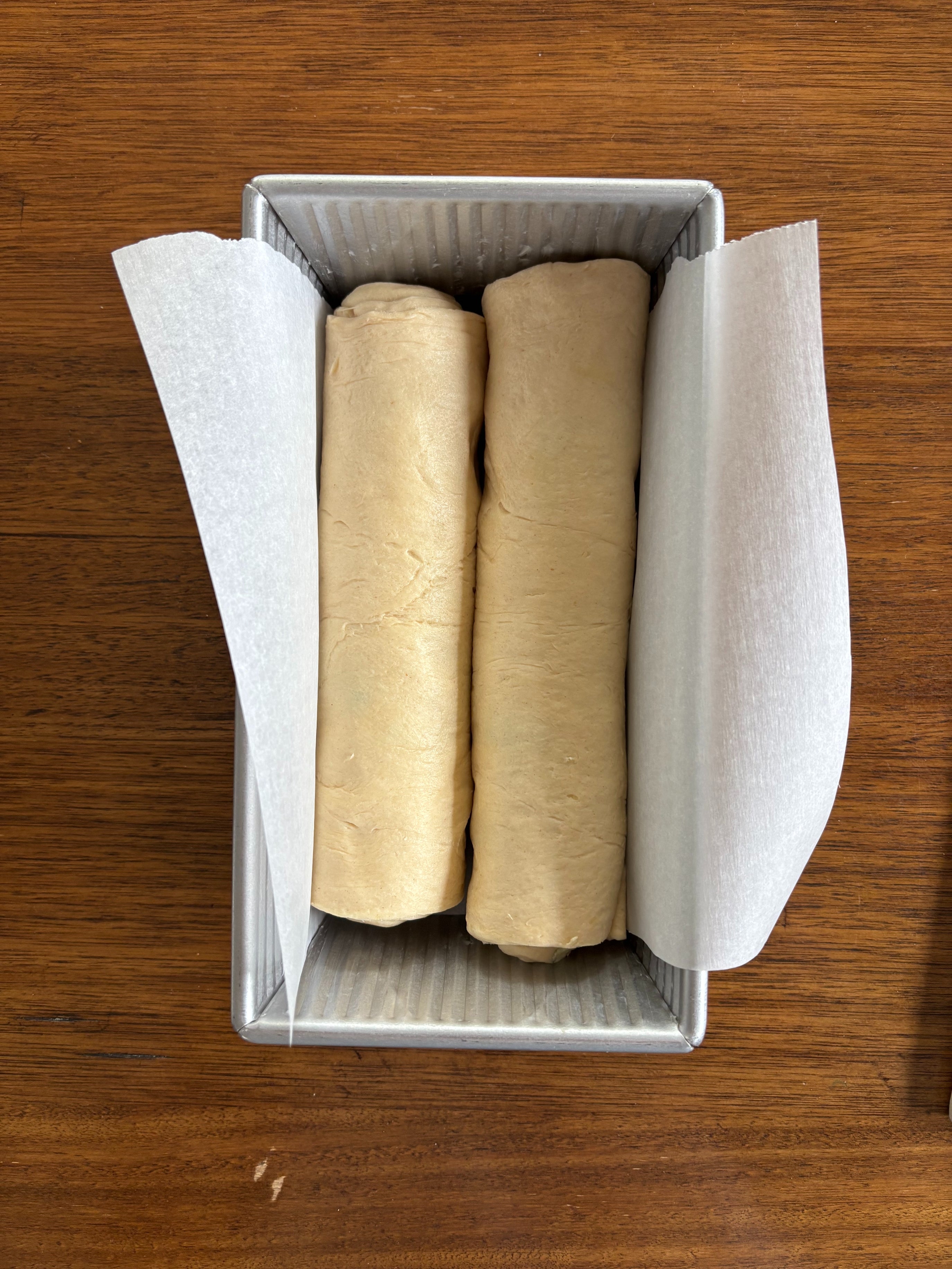 Two rolls of dough in a parchment-lined loaf pan