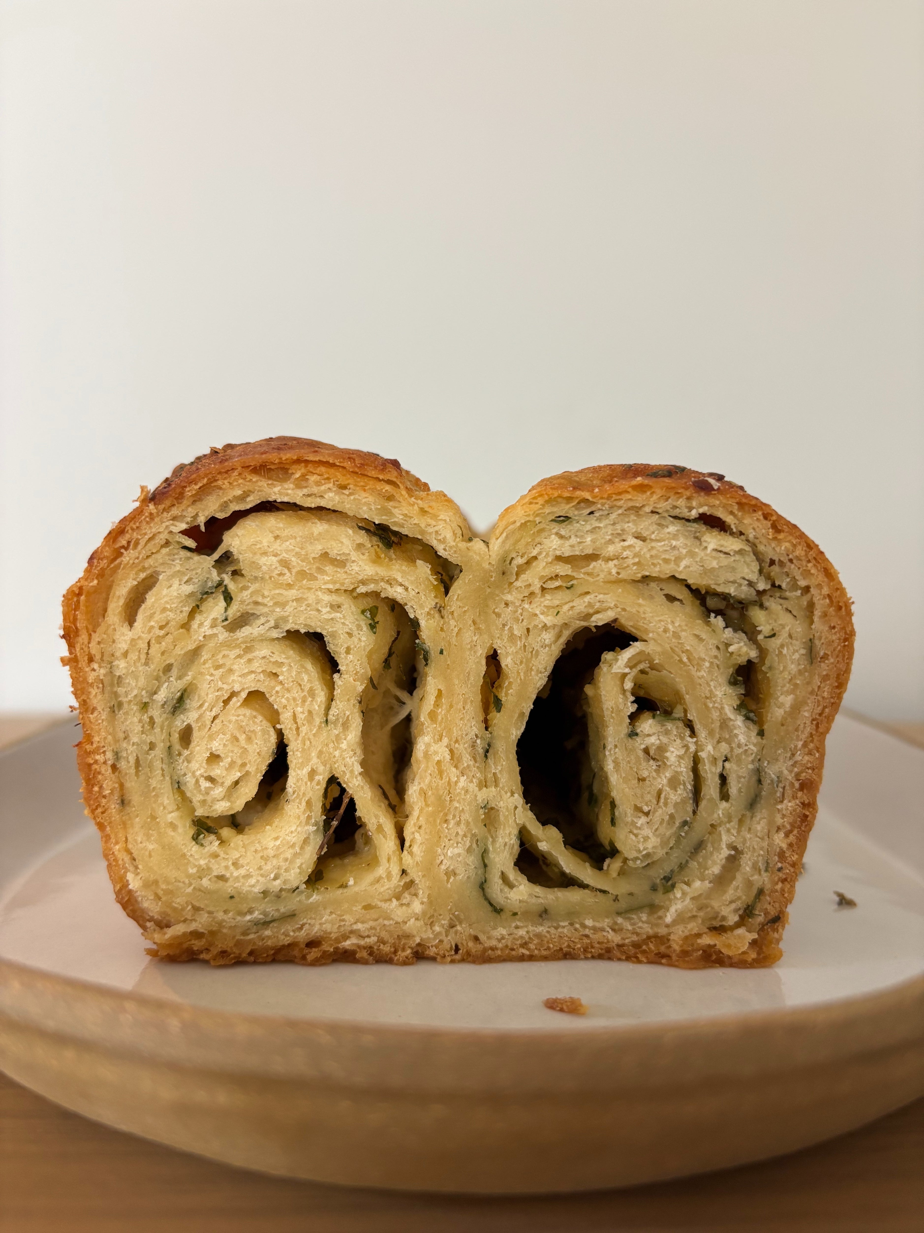 A close-up of a sliced, flaky pastry with a spiral pattern on a white plate