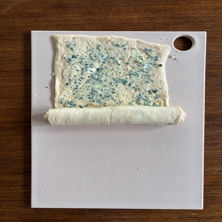 Dough on a cutting board being rolled up