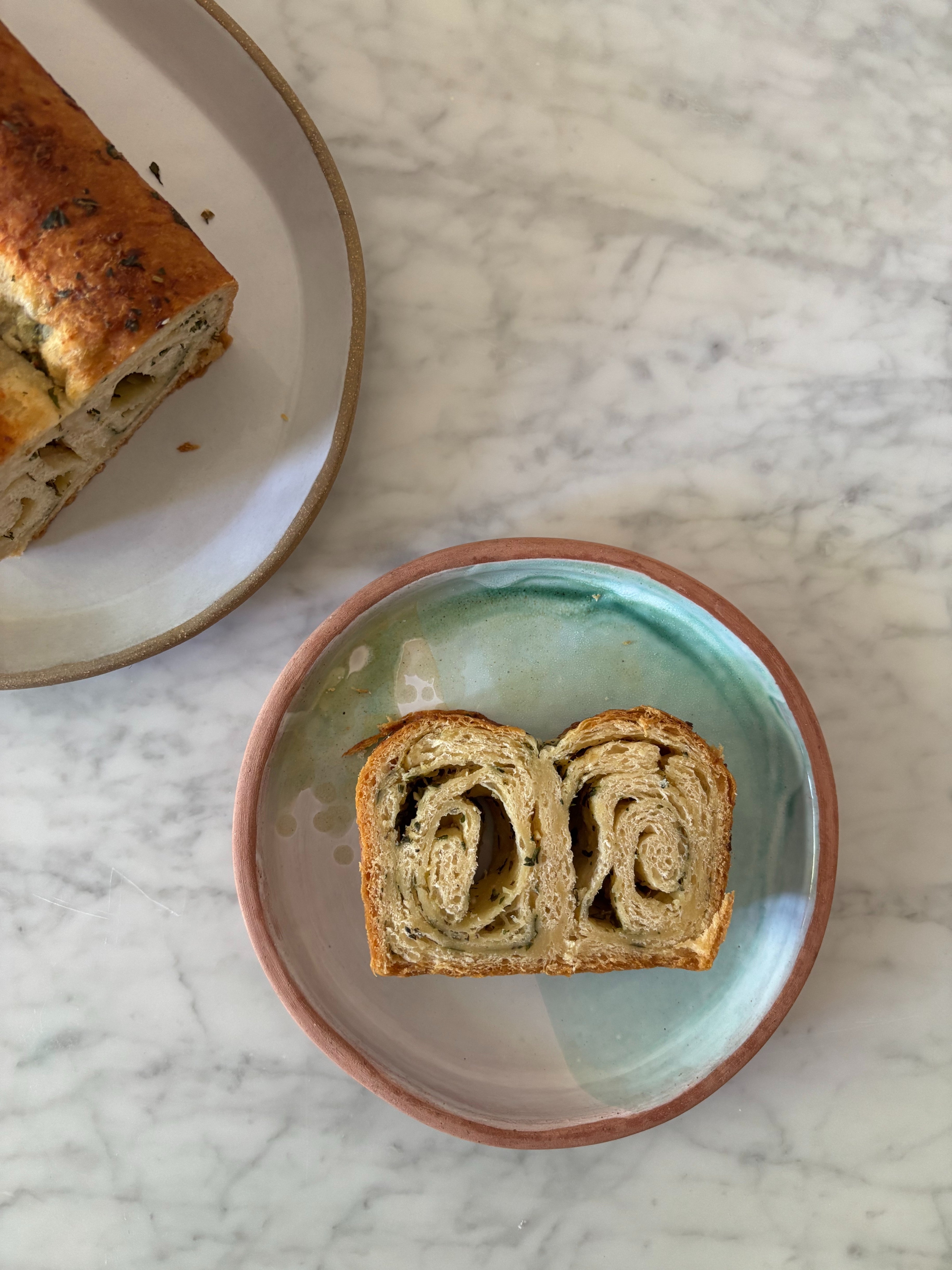 Two slices of swirled bread on a plate with a marble table background
