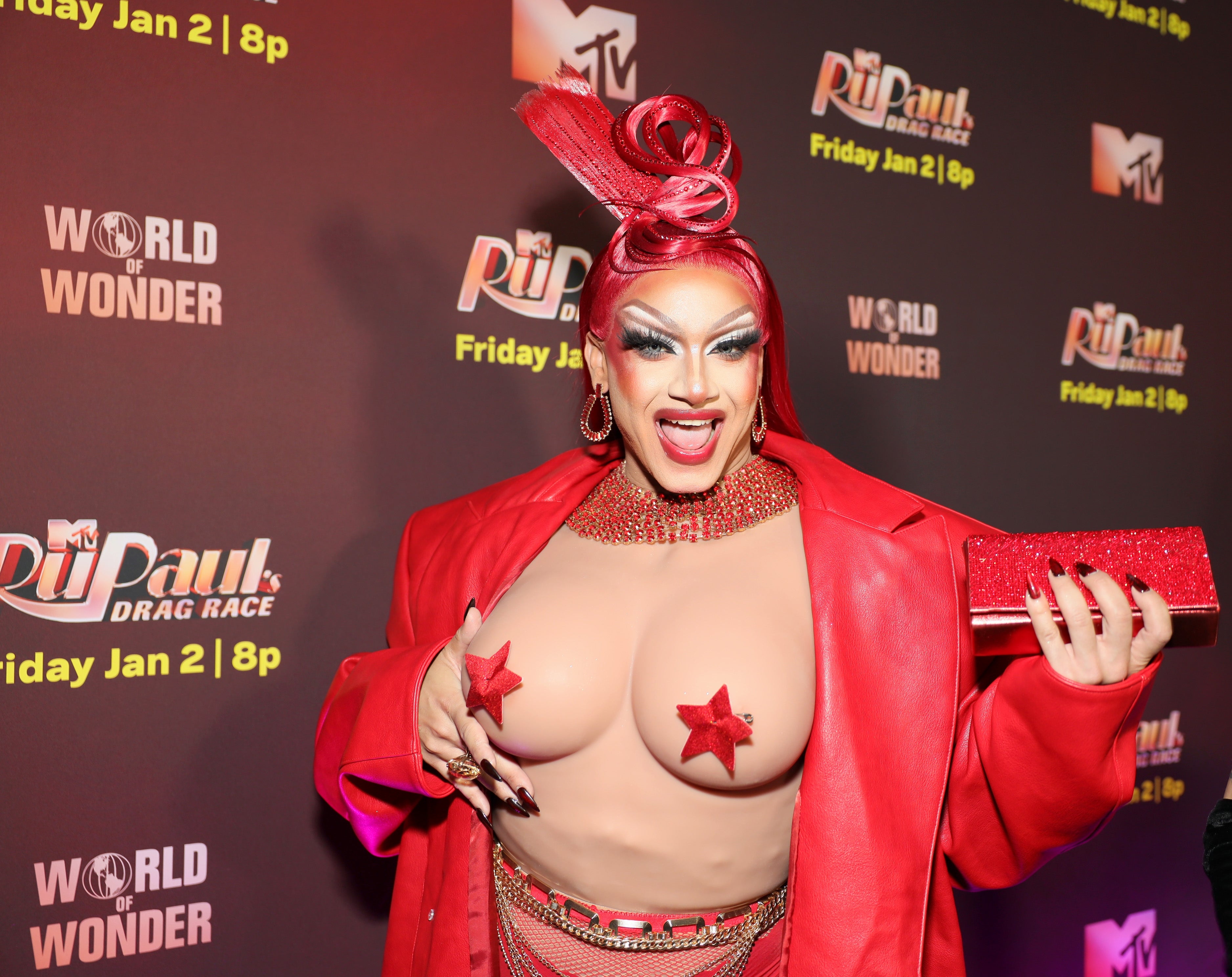 Mia Starr in bold outfit with star pasties, stylish makeup, and red accessories on a red carpet at a "RuPaul's Drag Race" event
