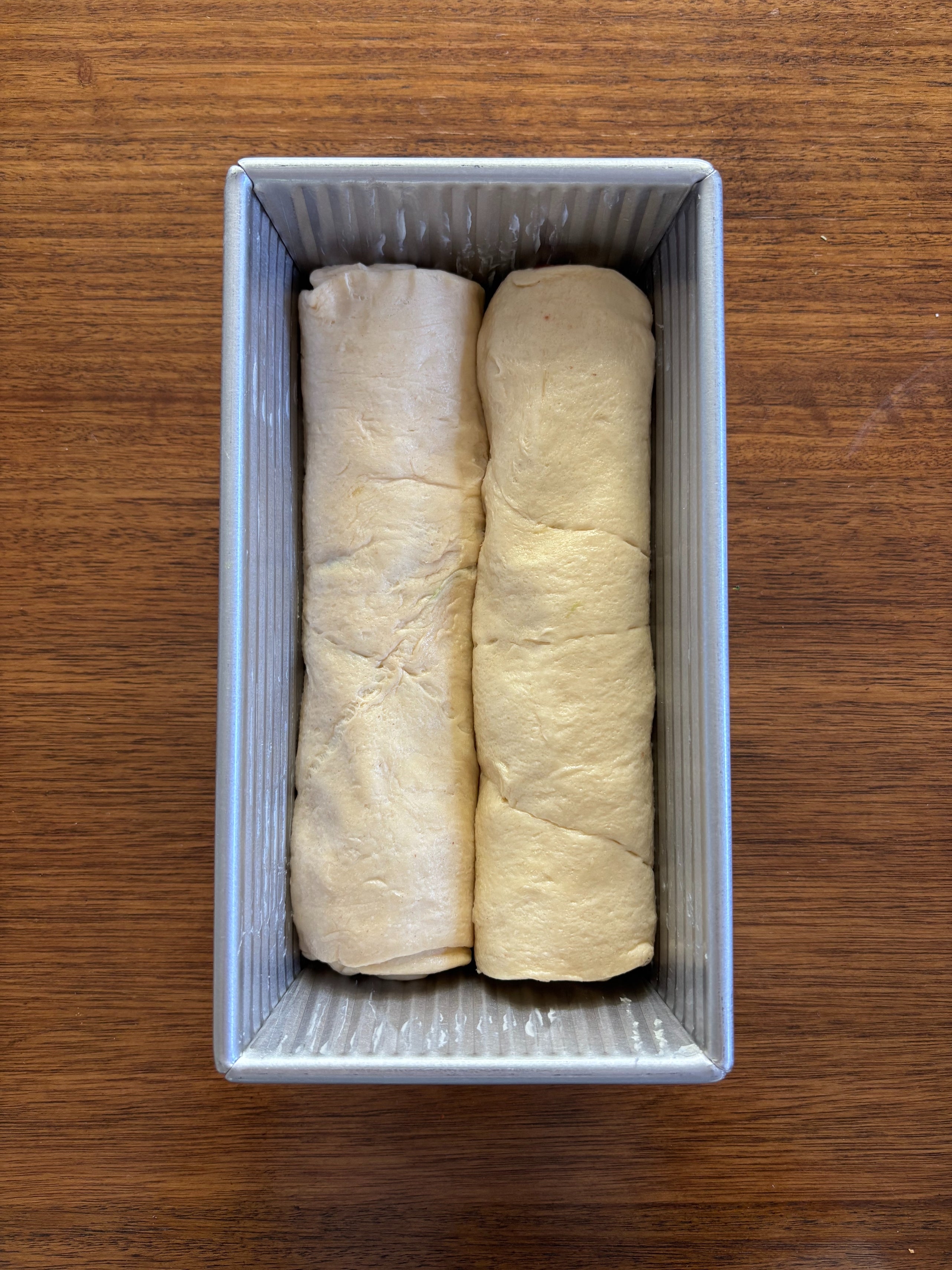Two logs of unbaked dough side by side in a loaf pan