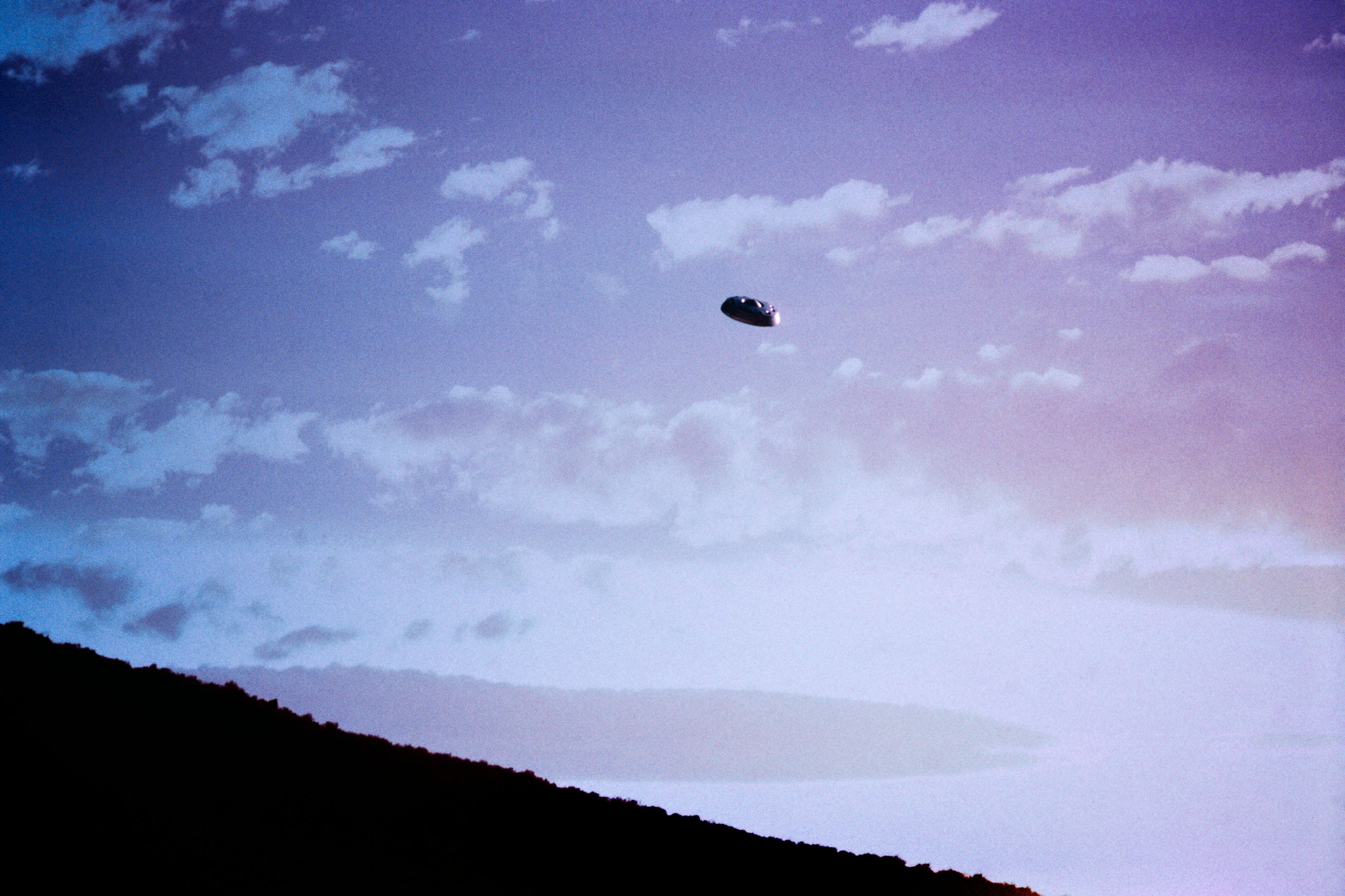 A classical  UFO photograph   with a disc-shaped entity  hovering successful  a cloudy entity  supra  a mountainous landscape