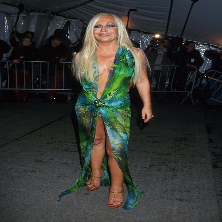 Person in a bold, tropical-patterned gown with a high slit and plunging neckline on a red carpet event