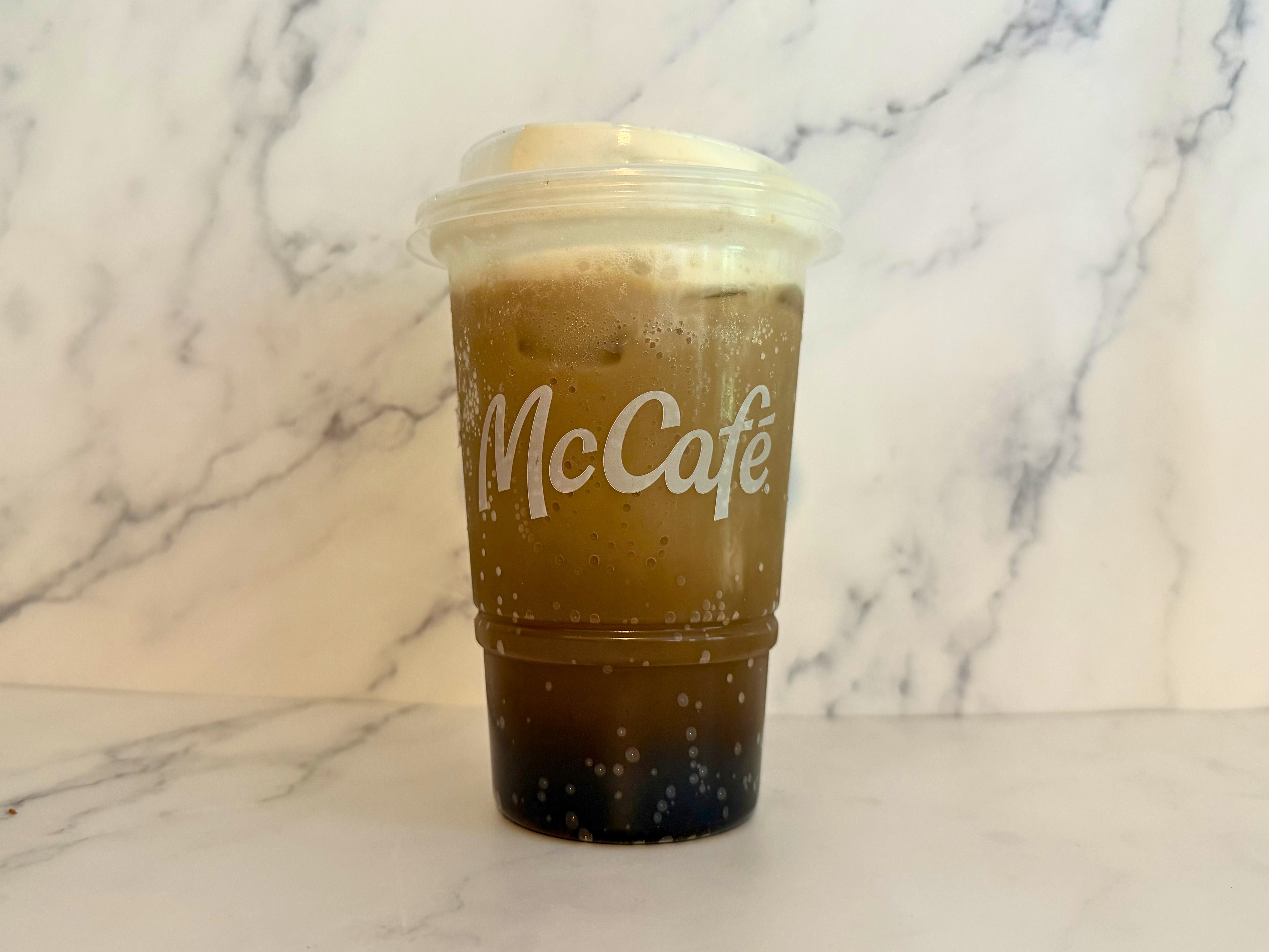 Dirty Dr Pepper in a clear McCafé cup with a marble background