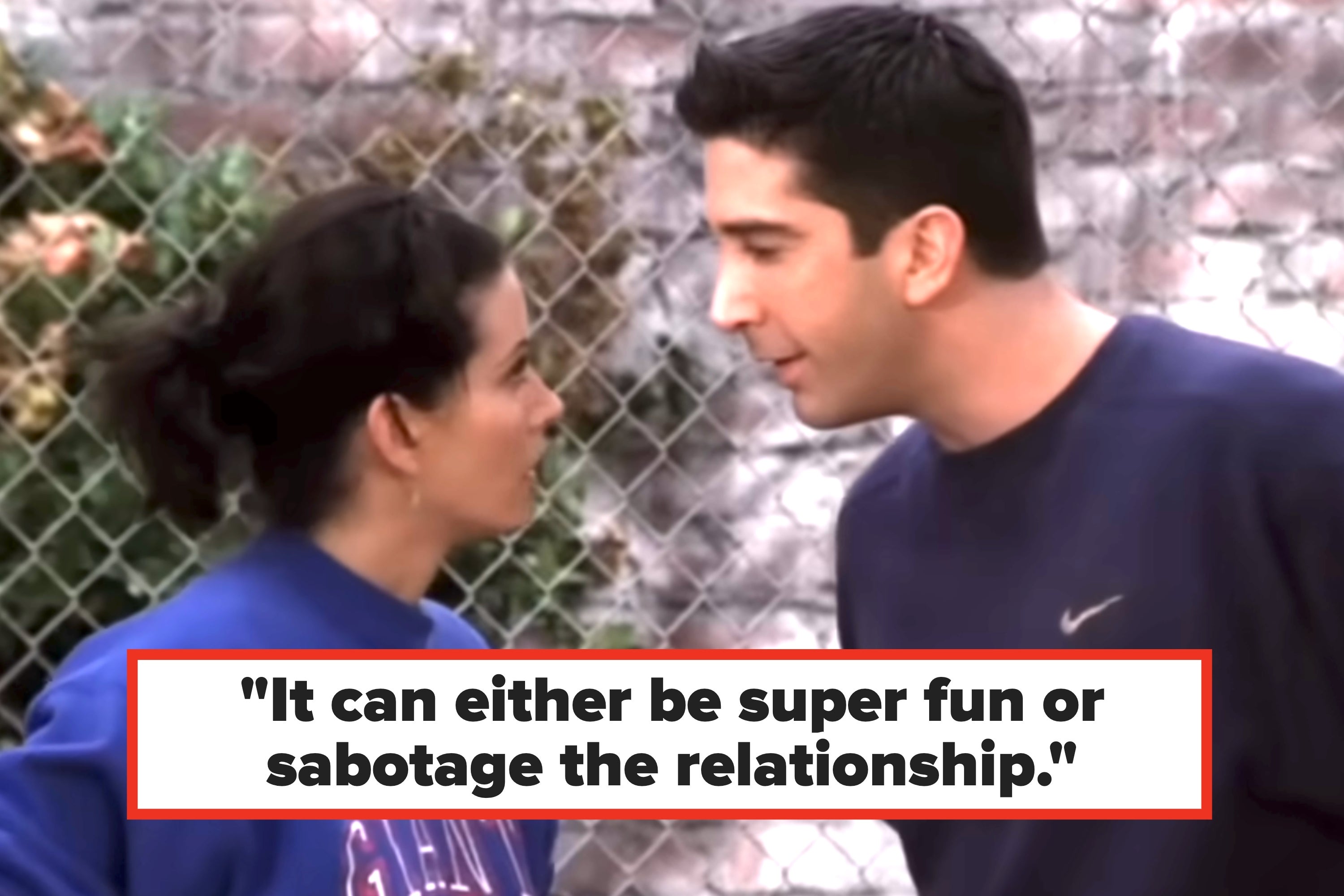 Two people in athletic wear face each other near a chain-link fence, engaged in an animated conversation
