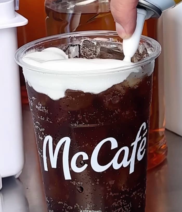 Iced McCafé drink with whipped cream being added on top