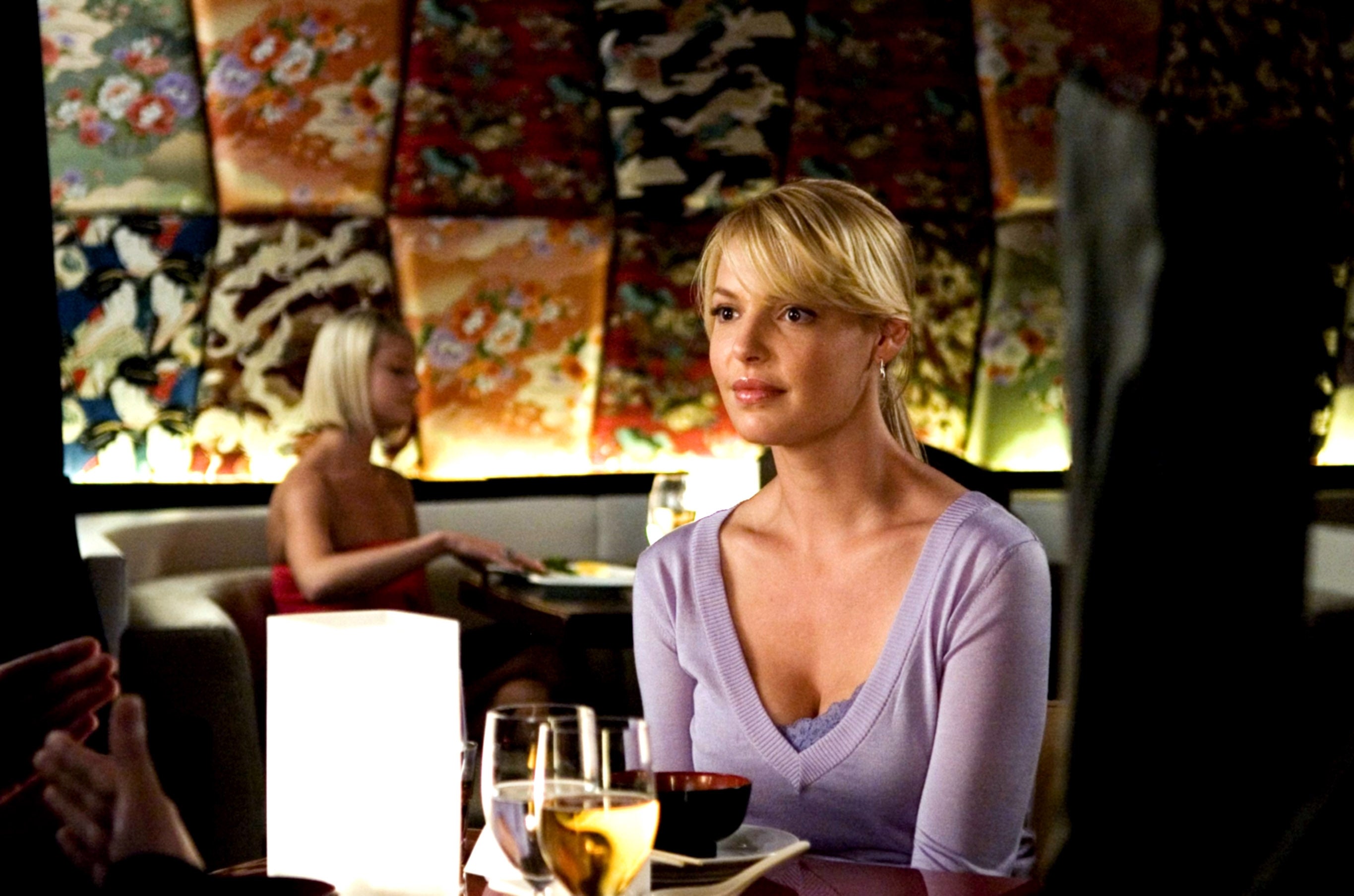 Woman with blond hairsbreadth  successful  a casual apical  sits astatine  a edifice  table, ambient mounting  with decorative partition  panels