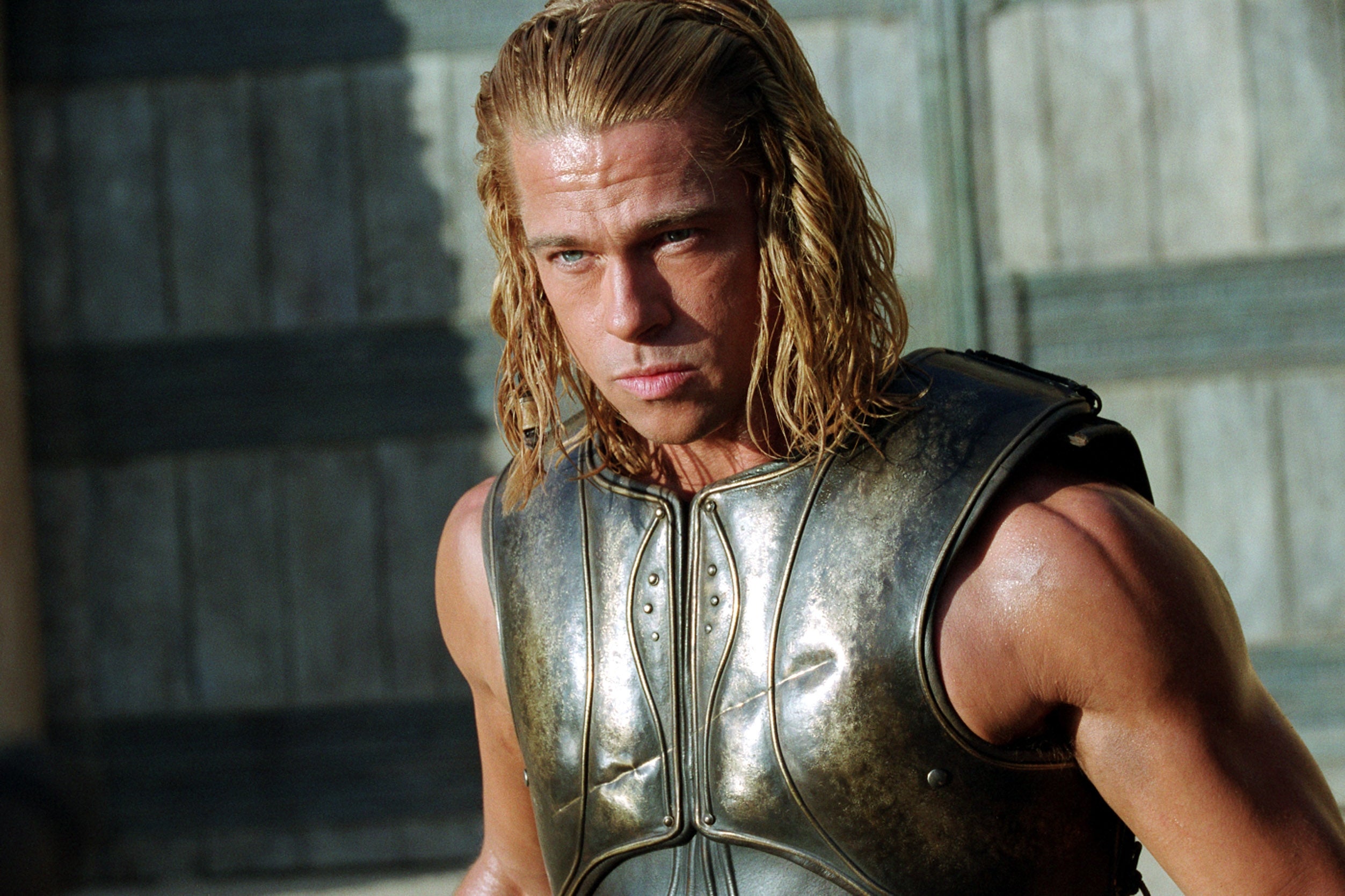 A idiosyncratic   successful  a gladiator-style metallic  armor, agelong  hair, stands with a superior   look  against a woody  backdrop