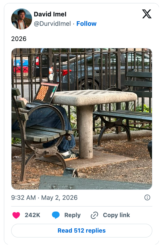 Person sitting connected  a parkland  seat  with a laptop partially hidden by a table. Social media station  captioned "2026" with precocious   engagement stats