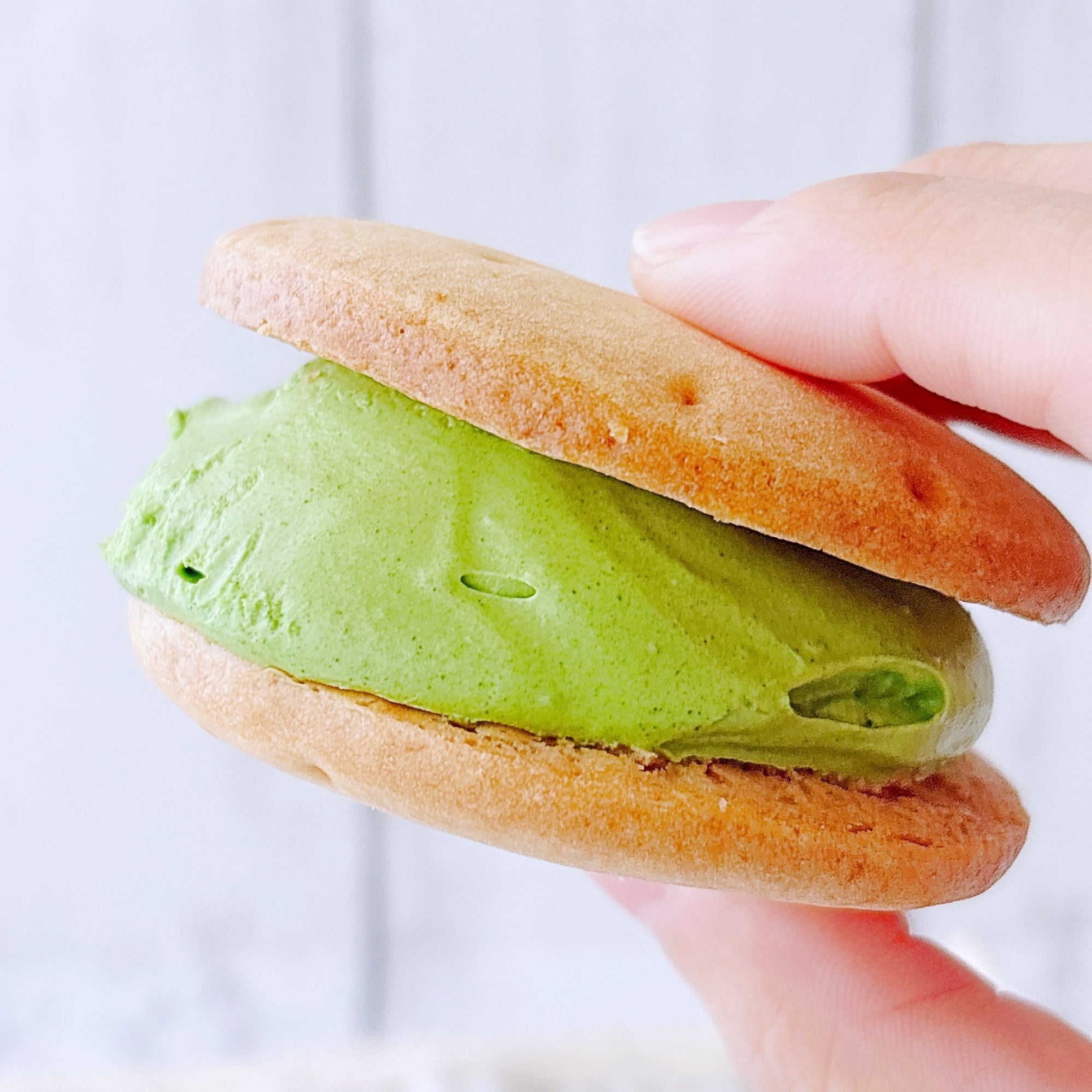 ローソンの「Uchi Café×森半 濃い抹茶しっとりビスケットサンド」手に持たれた様子のクローズアップ。