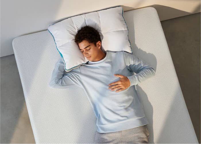 Orang tidur di kasur dengan bantal, mengenakan pakaian santai