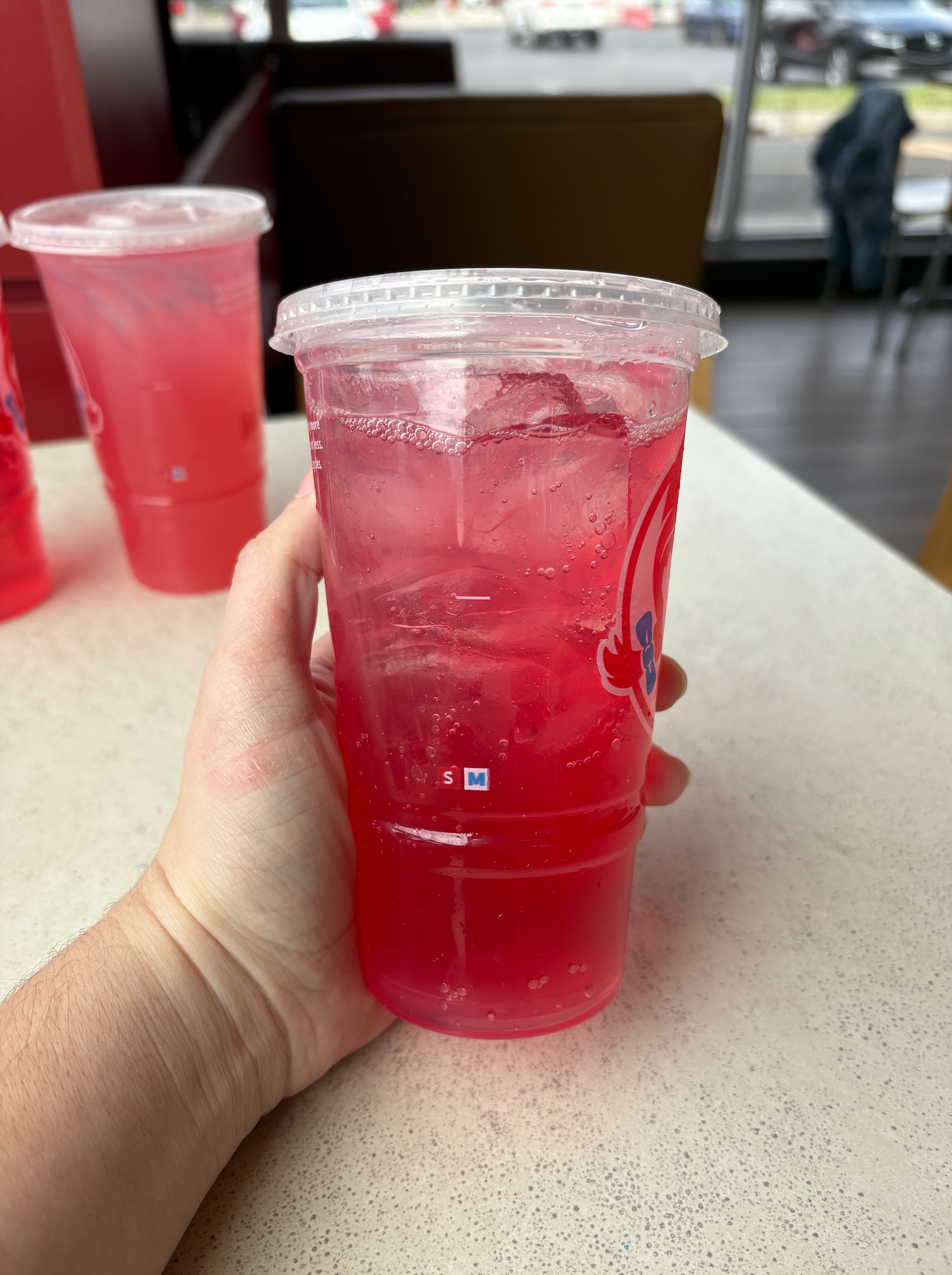 A hand holding a cup of Wendy's Sprite Watermelon