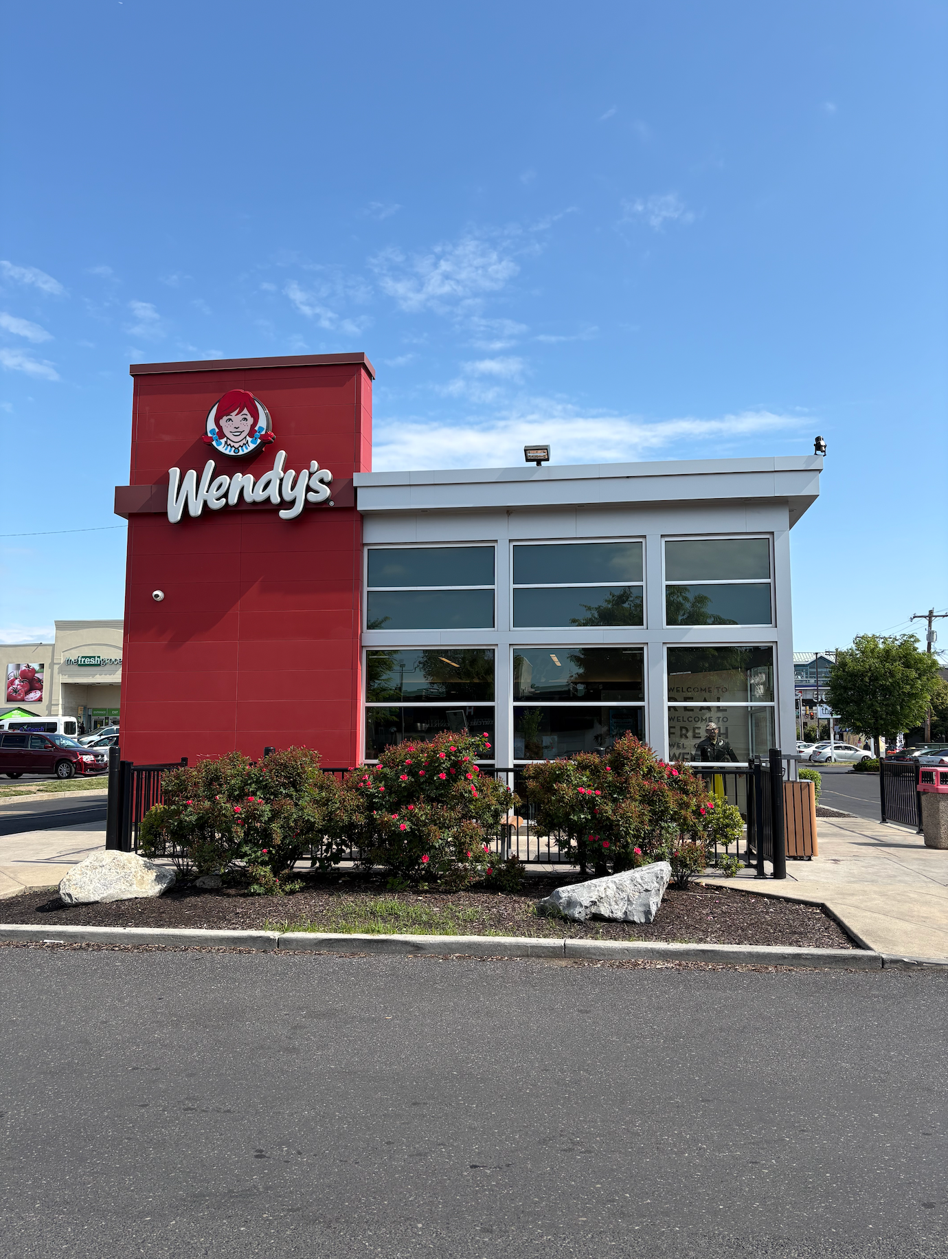 Exterior of a Wendy's fast food restaurant with large windows and a red sign featuring its logo