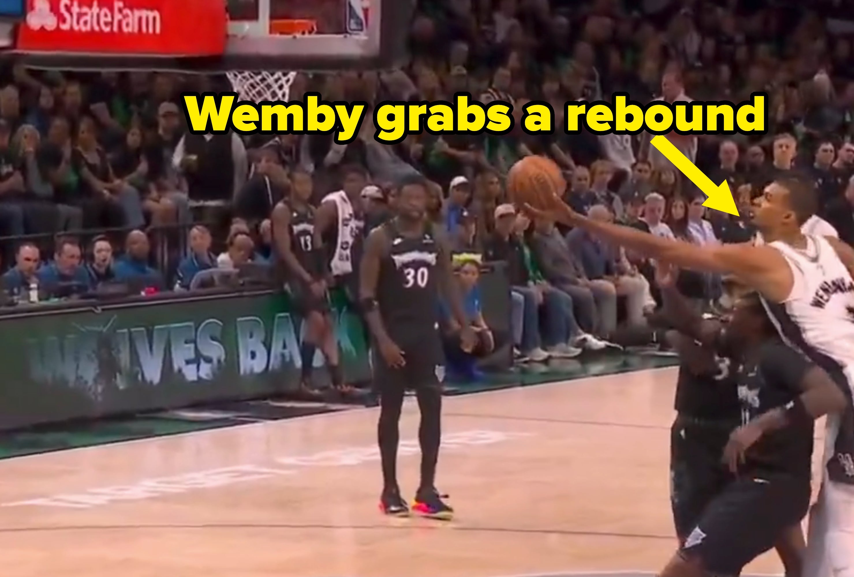 Basketball subordinate    makes a layup arsenic  defenders effort   to block, with assemblage  watching successful  an arena setting